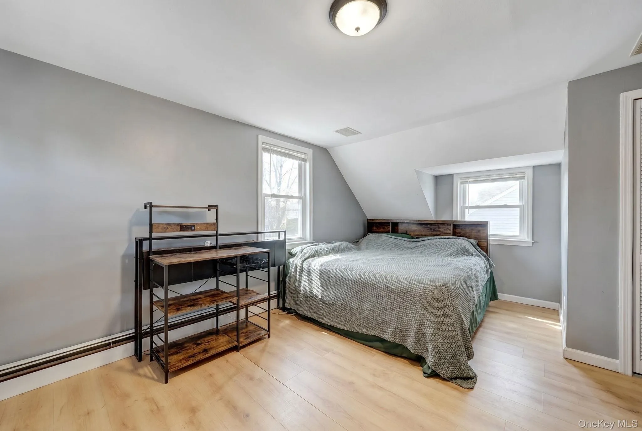 Room featuring wood-finish flooring, light grey painted walls, and an angled ceiling 2nd floor bedroom Room featuring wood-finish flooring, light grey painted walls, and an angled ceiling 2nd floor bedroom