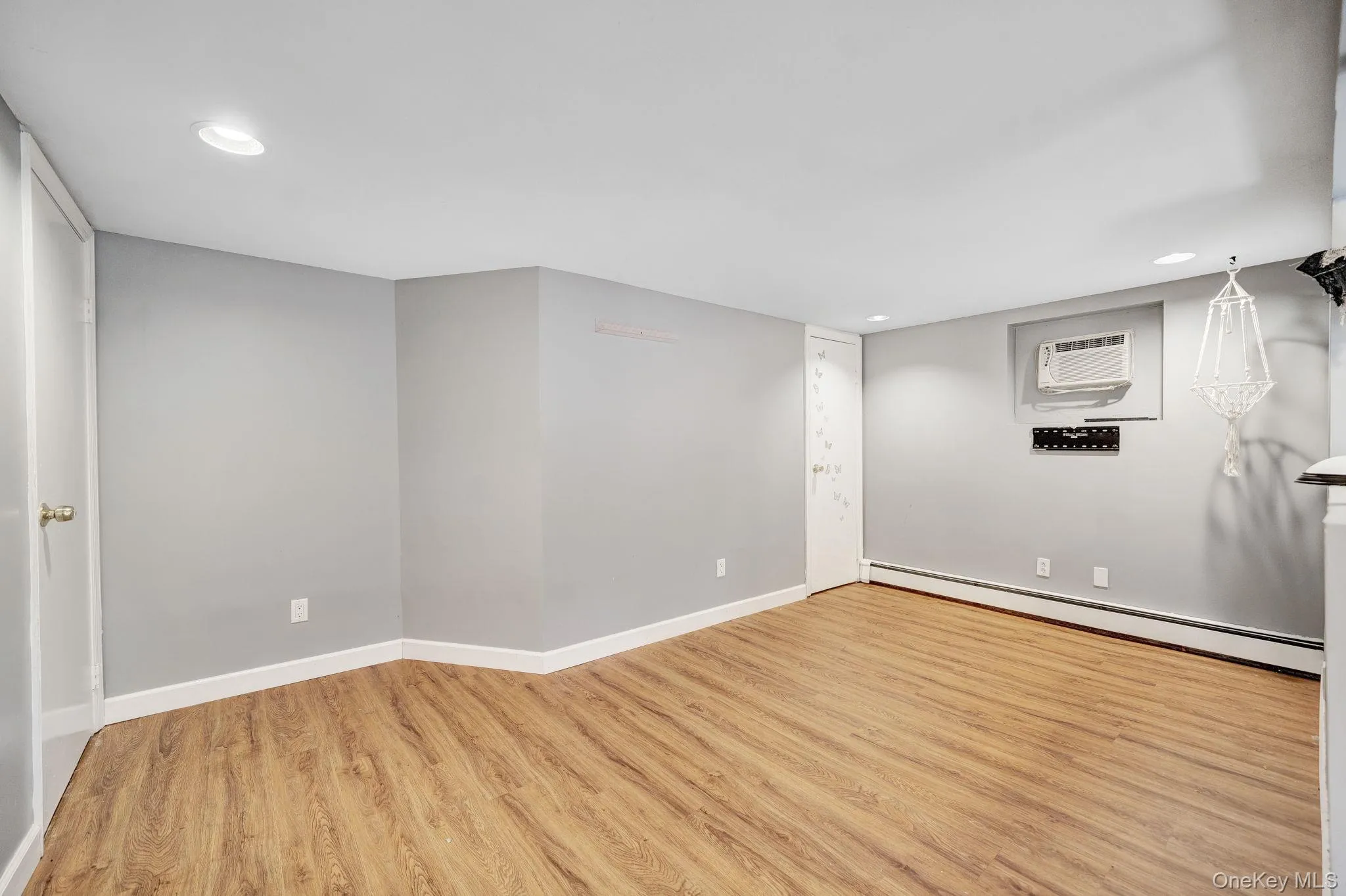 Spacious room featuring light wood-finish flooring, recessed lighting, and a neutral wall color Spacious room featuring light wood-finish flooring, recessed lighting, and a neutral wall color