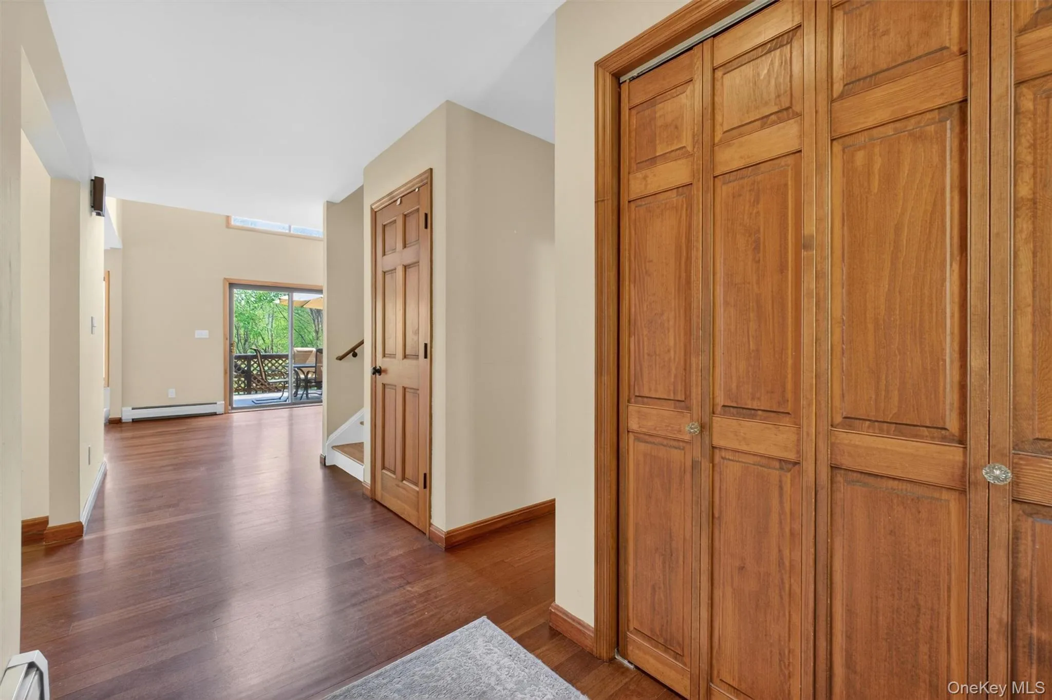 Entryway from front door with wood-finish flooring, bi-fold panel doors, and a sliding glass door offering outdoor access. Entryway from front door with wood-finish flooring, bi-fold panel doors, and a sliding glass door offering outdoor access.