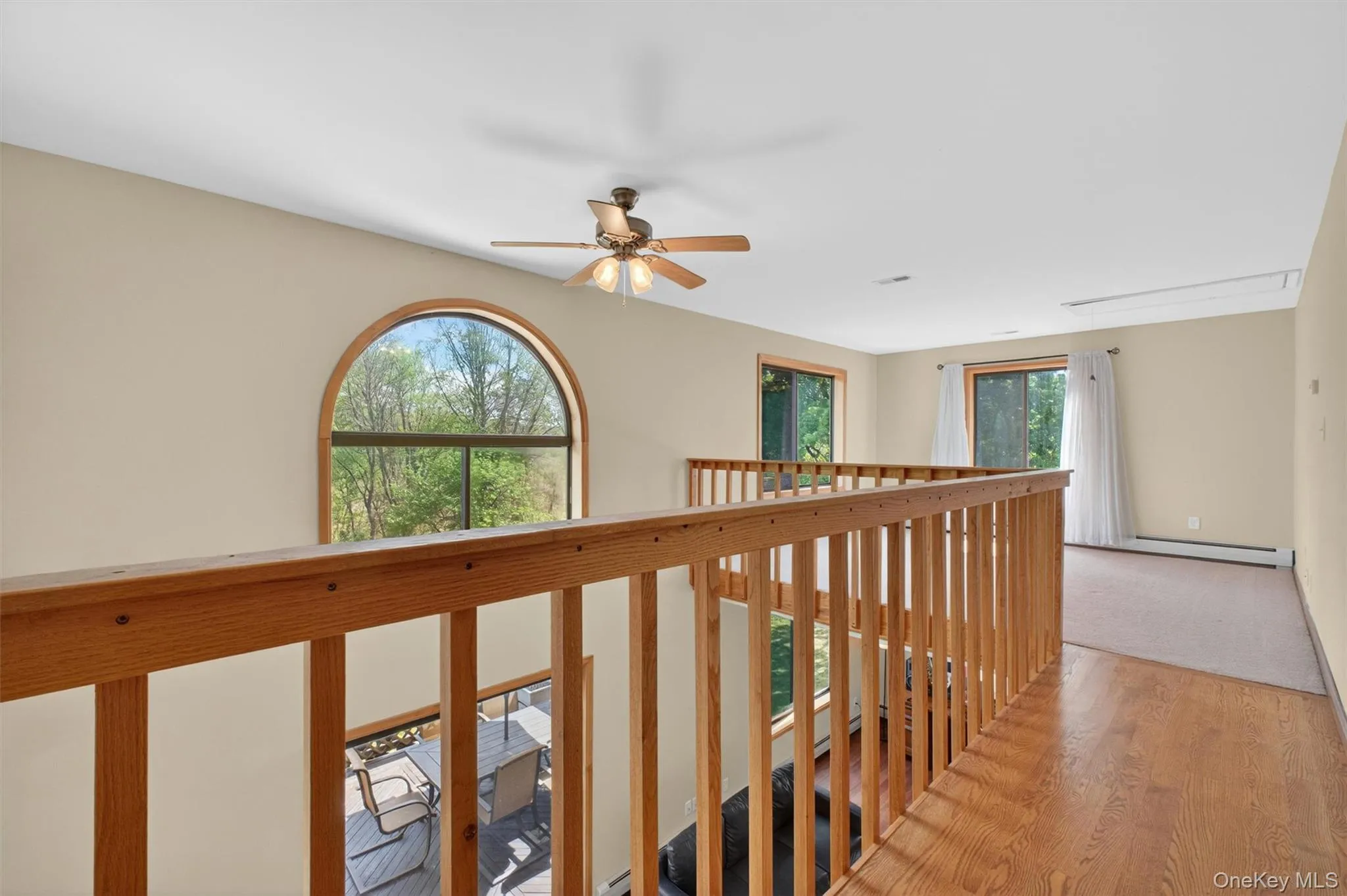 Upper-level loft with a wood railing and arched window that overlooks the lower level and filled with natural light. Upper-level loft with a wood railing and arched window that overlooks the lower level and filled with natural light.