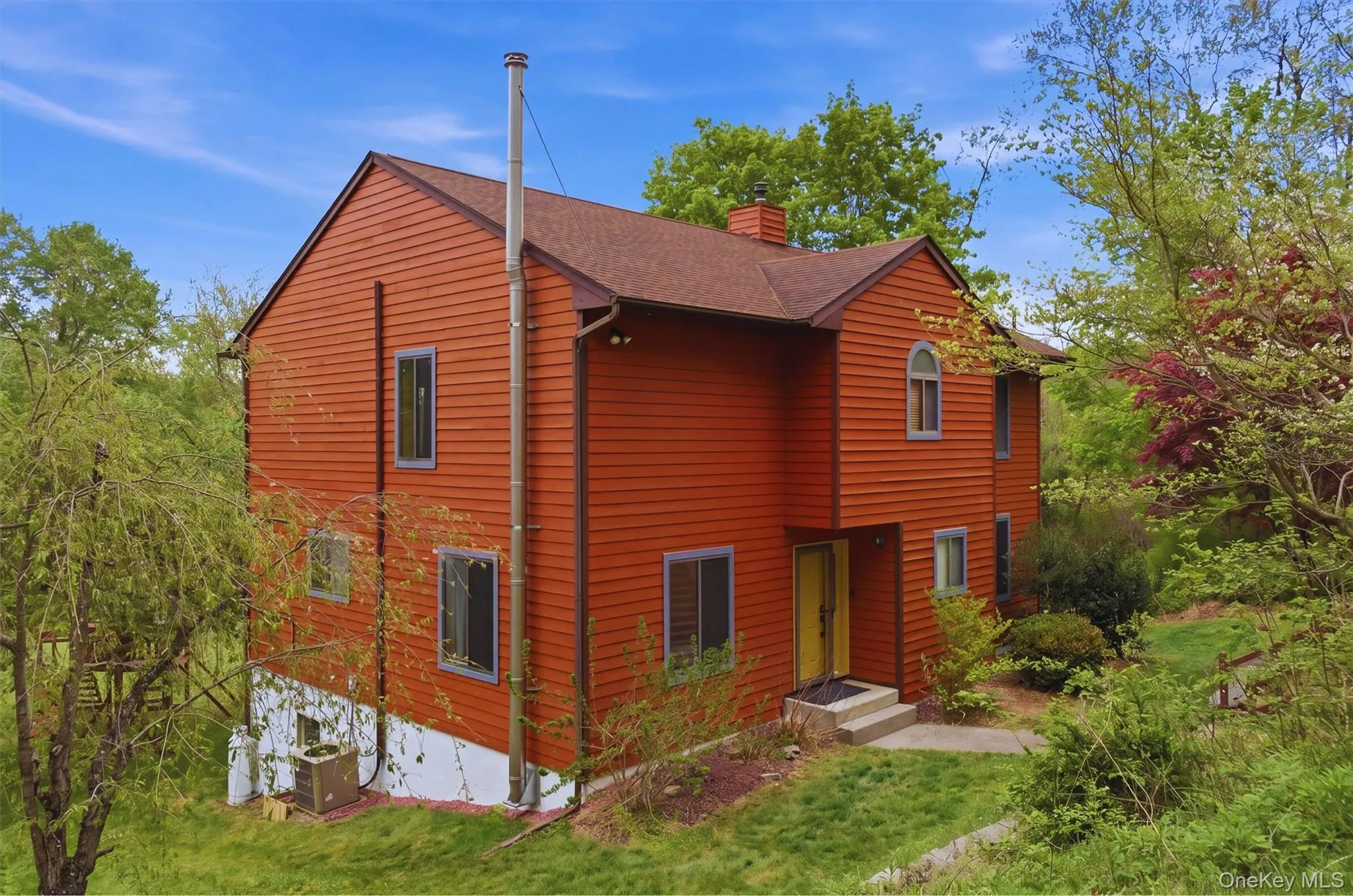 Red-toned house with a gabled roof set amidst mature trees and lush greenery. Red-toned house with a gabled roof set amidst mature trees and lush greenery.