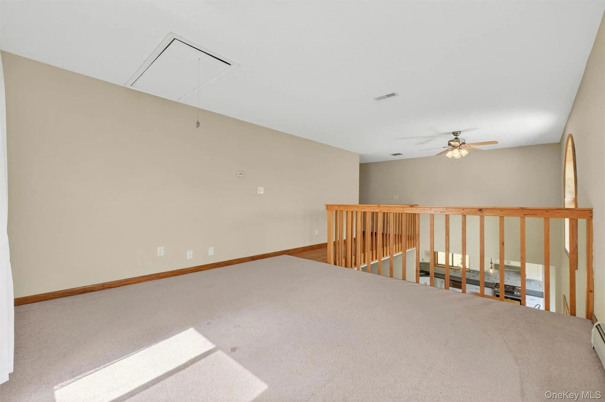 Carpeted loft area with wood-finish railing, vaulted ceiling, and an arched window, overlooking the first level. Carpeted loft area with wood-finish railing, vaulted ceiling, and an arched window, overlooking the first level.