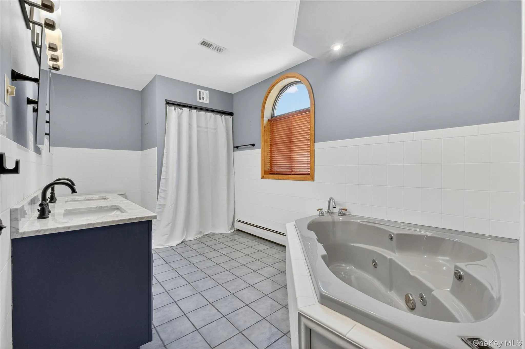 Bathroom featuring a jetted jacuzzi, dual vanity with undermount sinks and dark bronze fixtures, and a shower. Bathroom featuring a jetted jacuzzi, dual vanity with undermount sinks and dark bronze fixtures, and a shower.