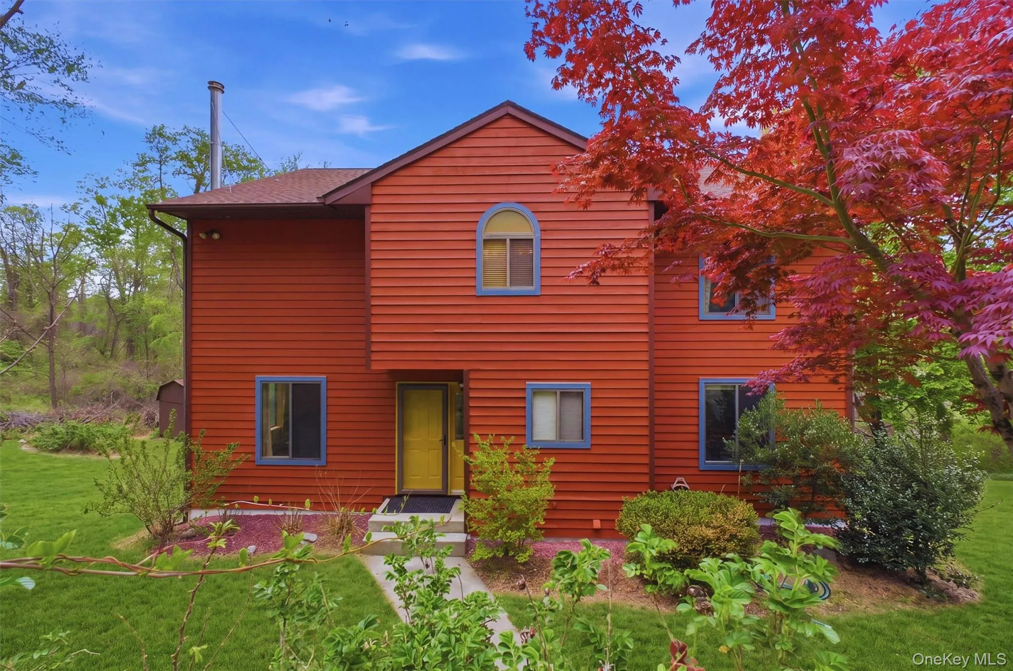Contemporary home featuring red siding and a prominent yellow entry door. Contemporary home featuring red siding and a prominent yellow entry door.