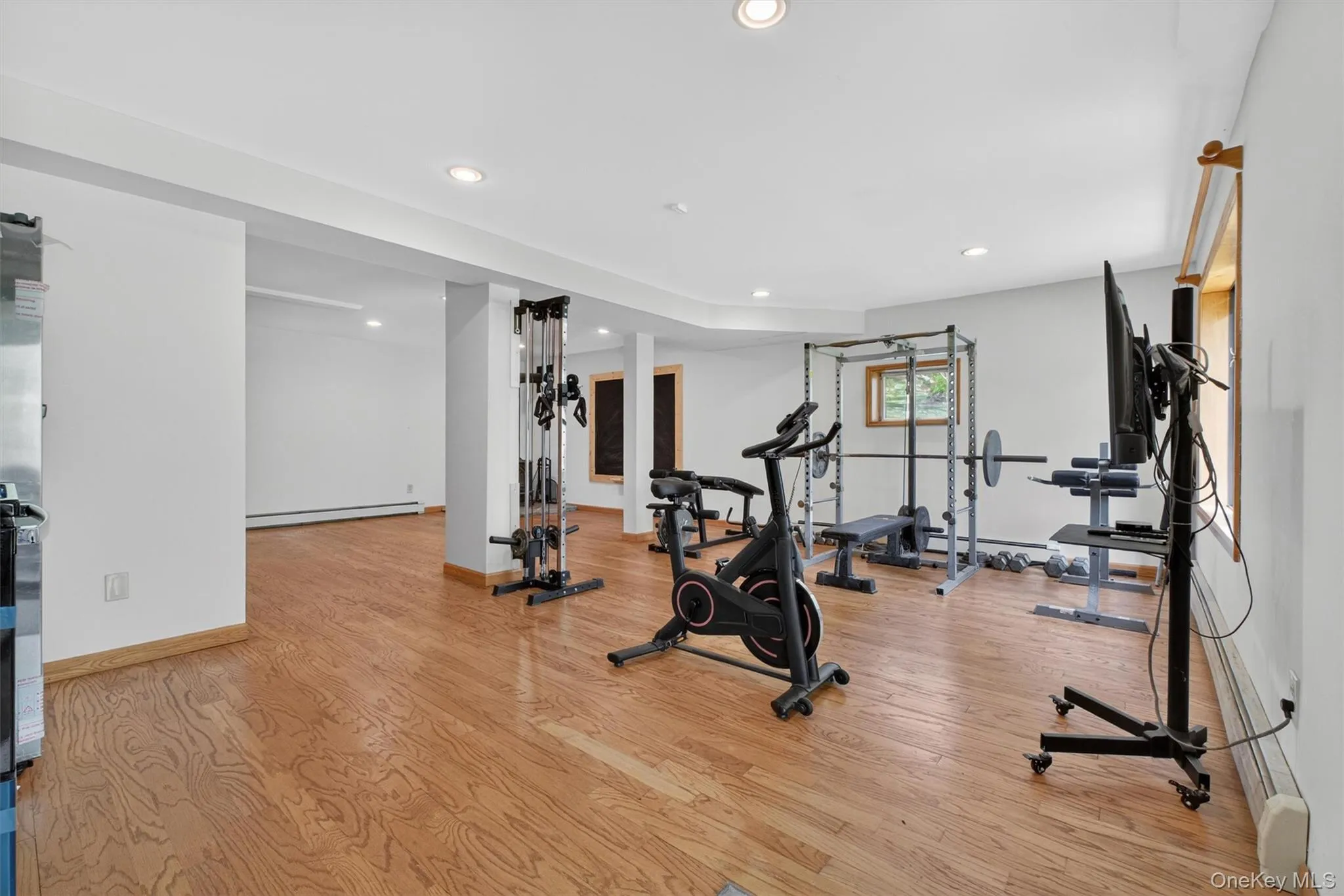 Spacious basement featuring wood-finish flooring, recessed lighting, and bright white walls. Spacious basement featuring wood-finish flooring, recessed lighting, and bright white walls.