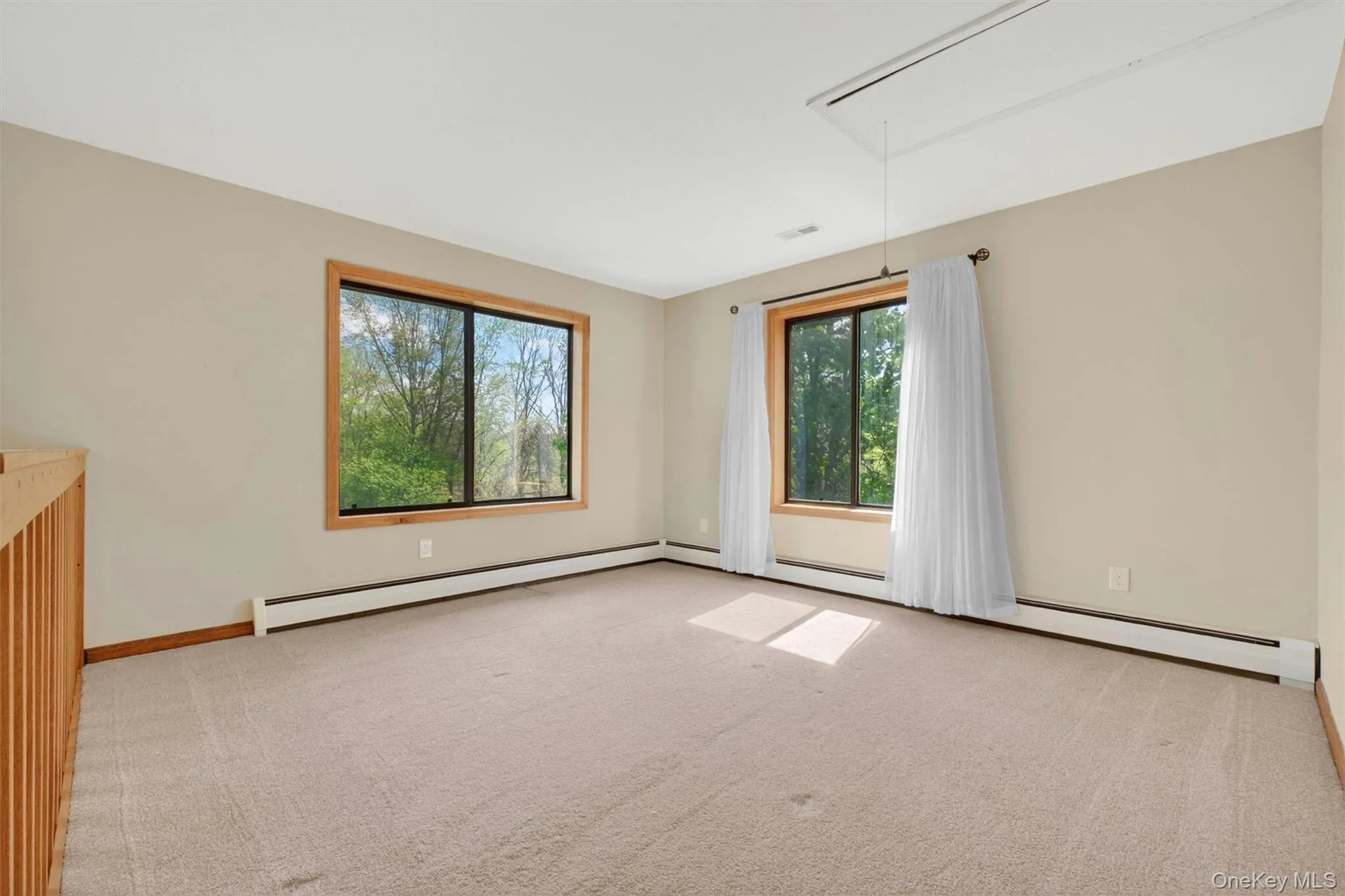 Upper-level loft with a wood railing that overlooks the lower level and filled with natural light. Upper-level loft with a wood railing that overlooks the lower level and filled with natural light.
