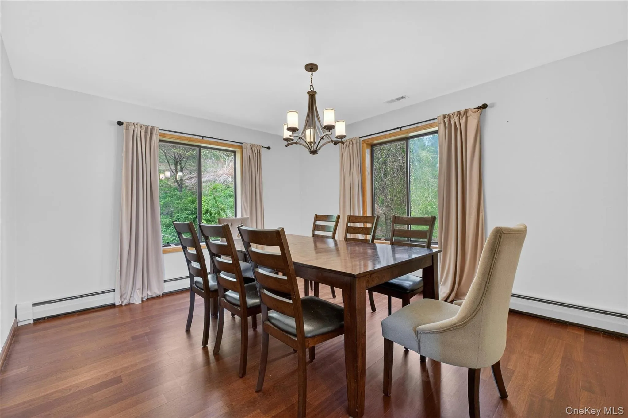 Dining area featuring wood-finish flooring, two large windows, and a chandelier Dining area featuring wood-finish flooring, two large windows, and a chandelier