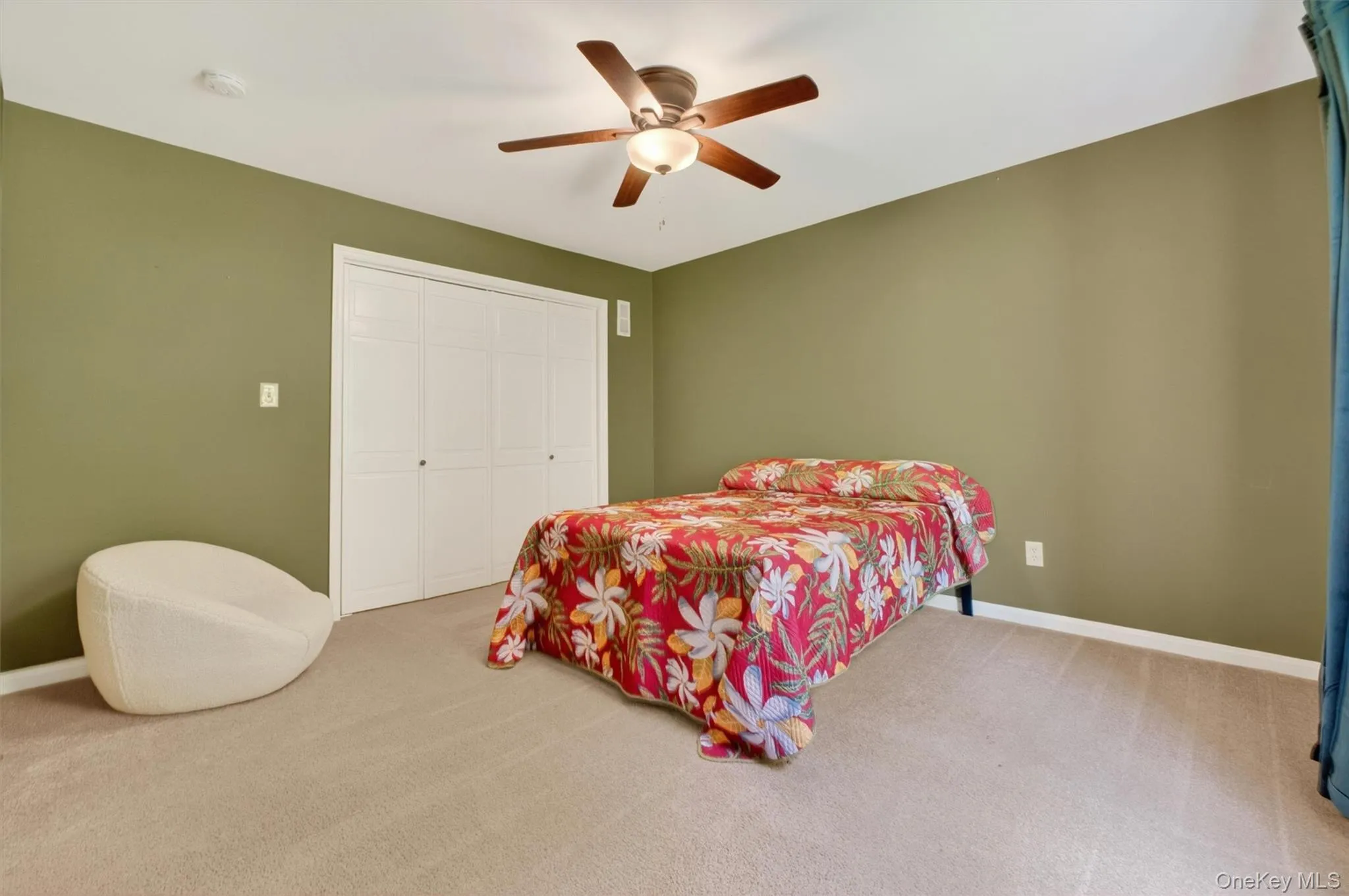 Large bedroom featuring neutral-toned carpeting, olive green walls, and white trim. Large bedroom featuring neutral-toned carpeting, olive green walls, and white trim.