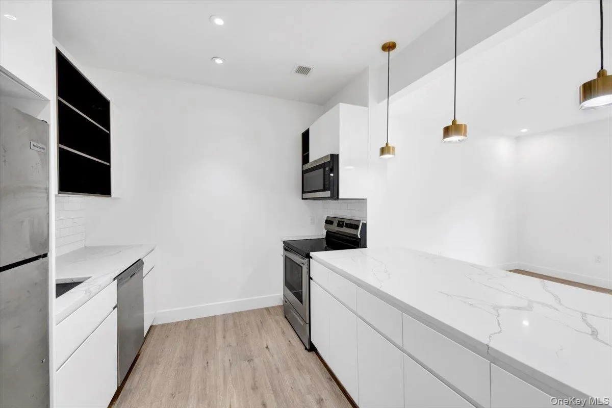 Modern kitchen featuring white cabinetry, light wood-finish flooring, and white quartz-finish countertops Modern kitchen featuring white cabinetry, light wood-finish flooring, and white quartz-finish countertops