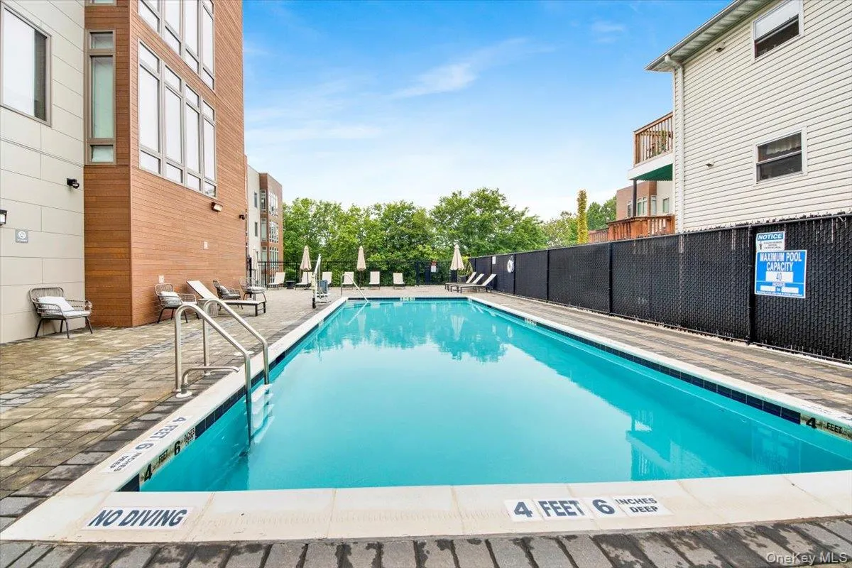 Outdoor swimming pool featuring stainless steel handrails, a surrounding paver patio, and perimeter fencing Outdoor swimming pool featuring stainless steel handrails, a surrounding paver patio, and perimeter fencing