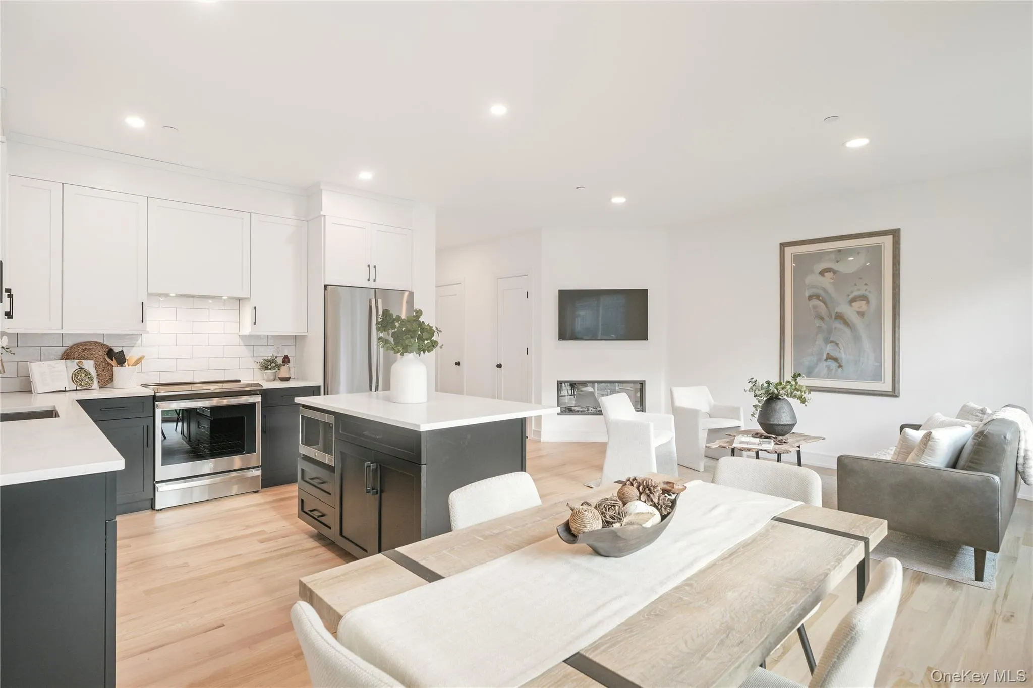 Kitchen featuring a kitchen island, tasteful backsplash, white cabinetry, stainless steel appliances, and light wood-type flooring Kitchen featuring a kitchen island, tasteful backsplash, white cabinetry, stainless steel appliances, and light wood-type flooring