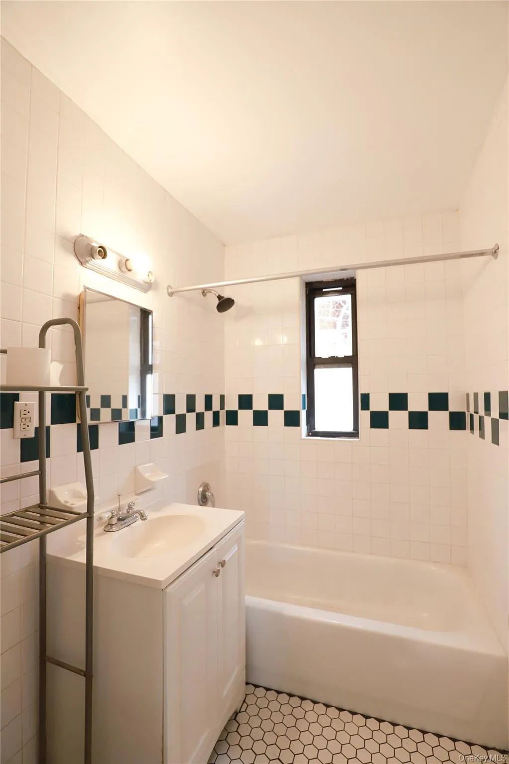 Bathroom featuring white subway tile walls, a checkerboard accent tile, a white vanity with integrated sink, chrome fixtures, and hexagonal floor tiling Bathroom featuring white subway tile walls, a checkerboard accent tile, a white vanity with integrated sink, chrome fixtures, and hexagonal floor tiling