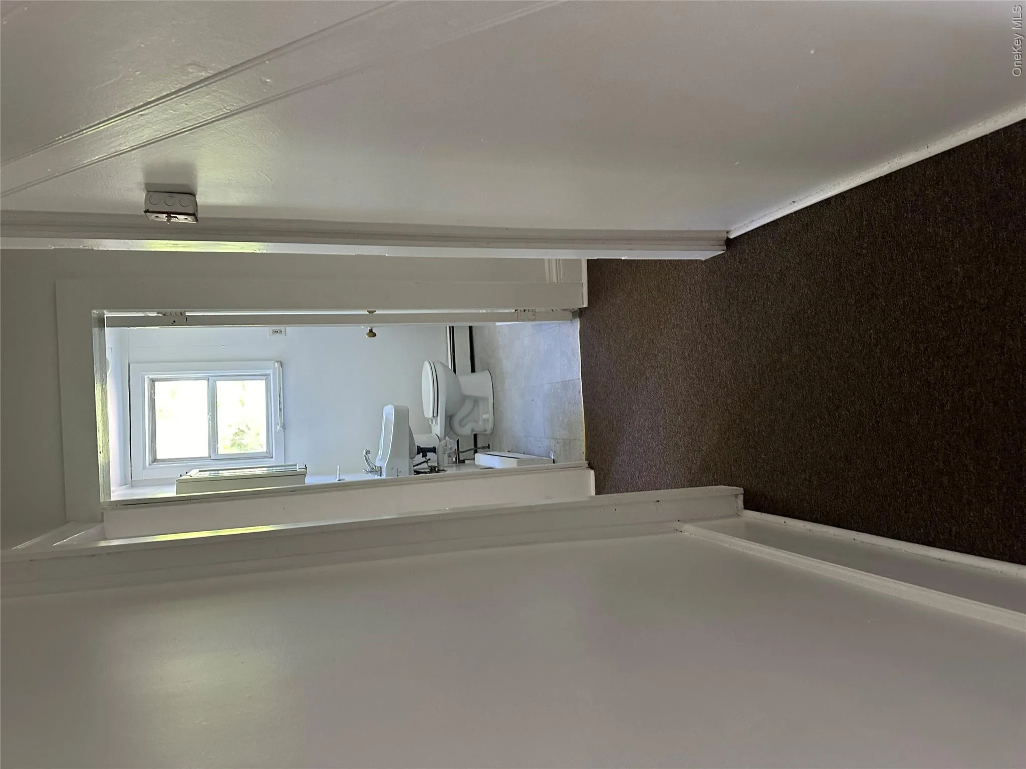 Hallway featuring baseboard heating, sink, and dark carpet Hallway featuring baseboard heating, sink, and dark carpet