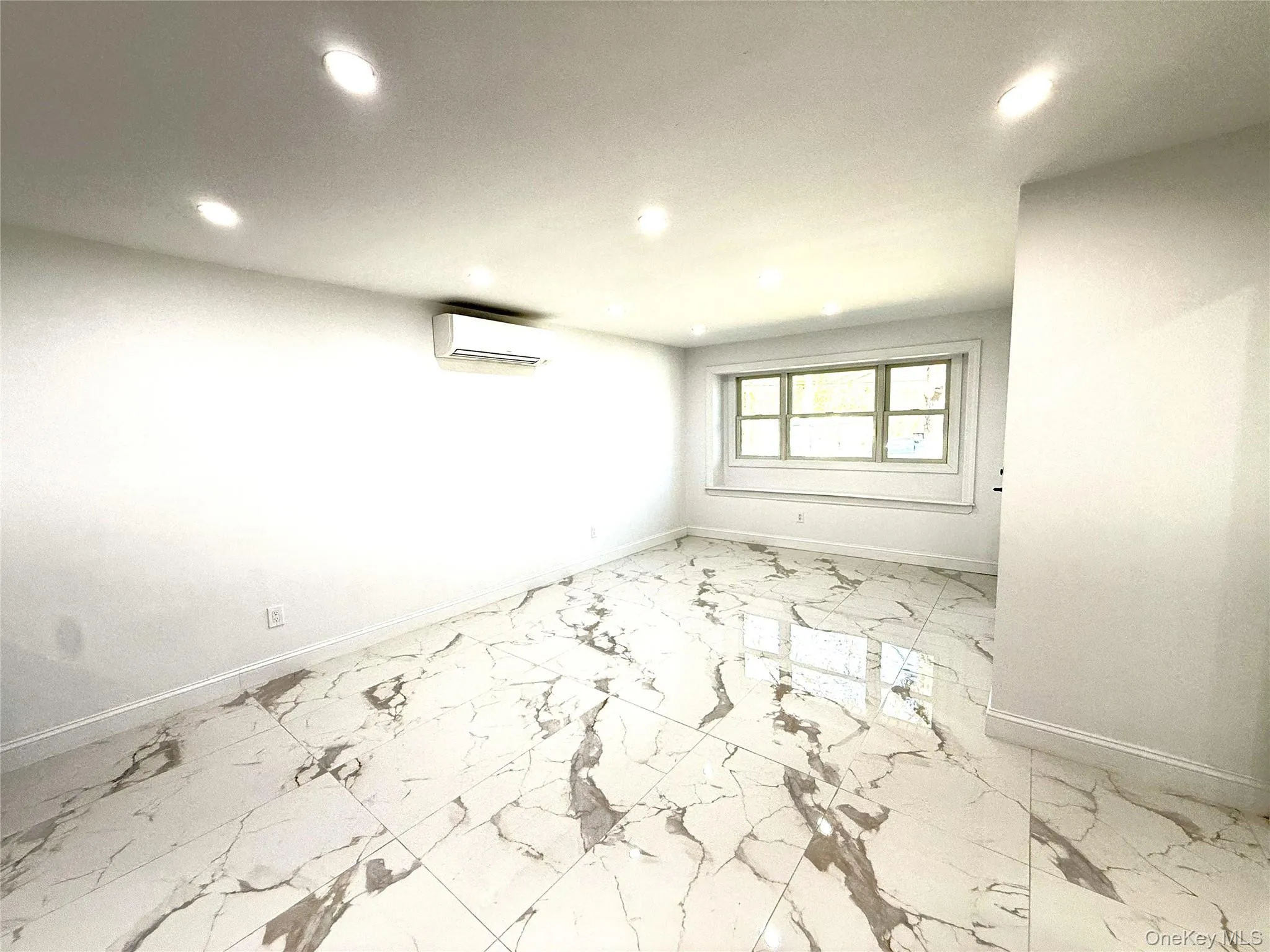 Spacious room featuring large format tile flooring with veining, recessed ceiling lighting, and a ductless mini-split system Spacious room featuring large format tile flooring with veining, recessed ceiling lighting, and a ductless mini-split system