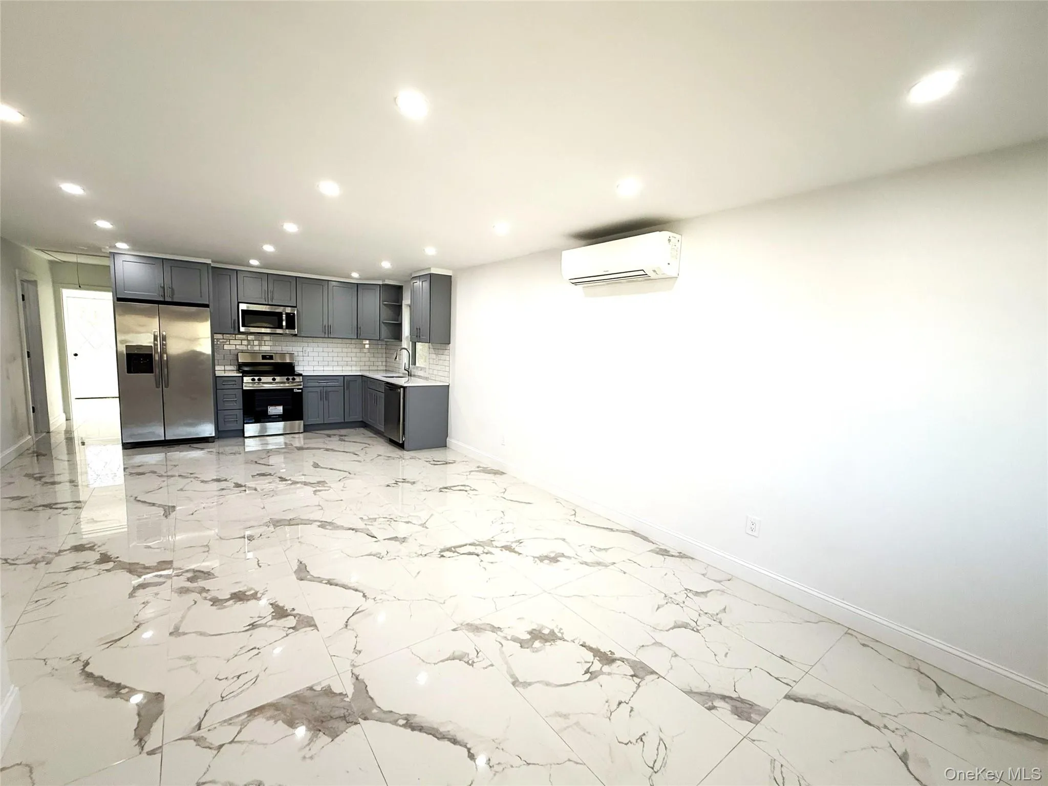 Contemporary kitchen space featuring white marble-look flooring, gray cabinetry, stainless steel appliances, a white subway tile backsplash, and recessed lighting Contemporary kitchen space featuring white marble-look flooring, gray cabinetry, stainless steel appliances, a white subway tile backsplash, and recessed lighting