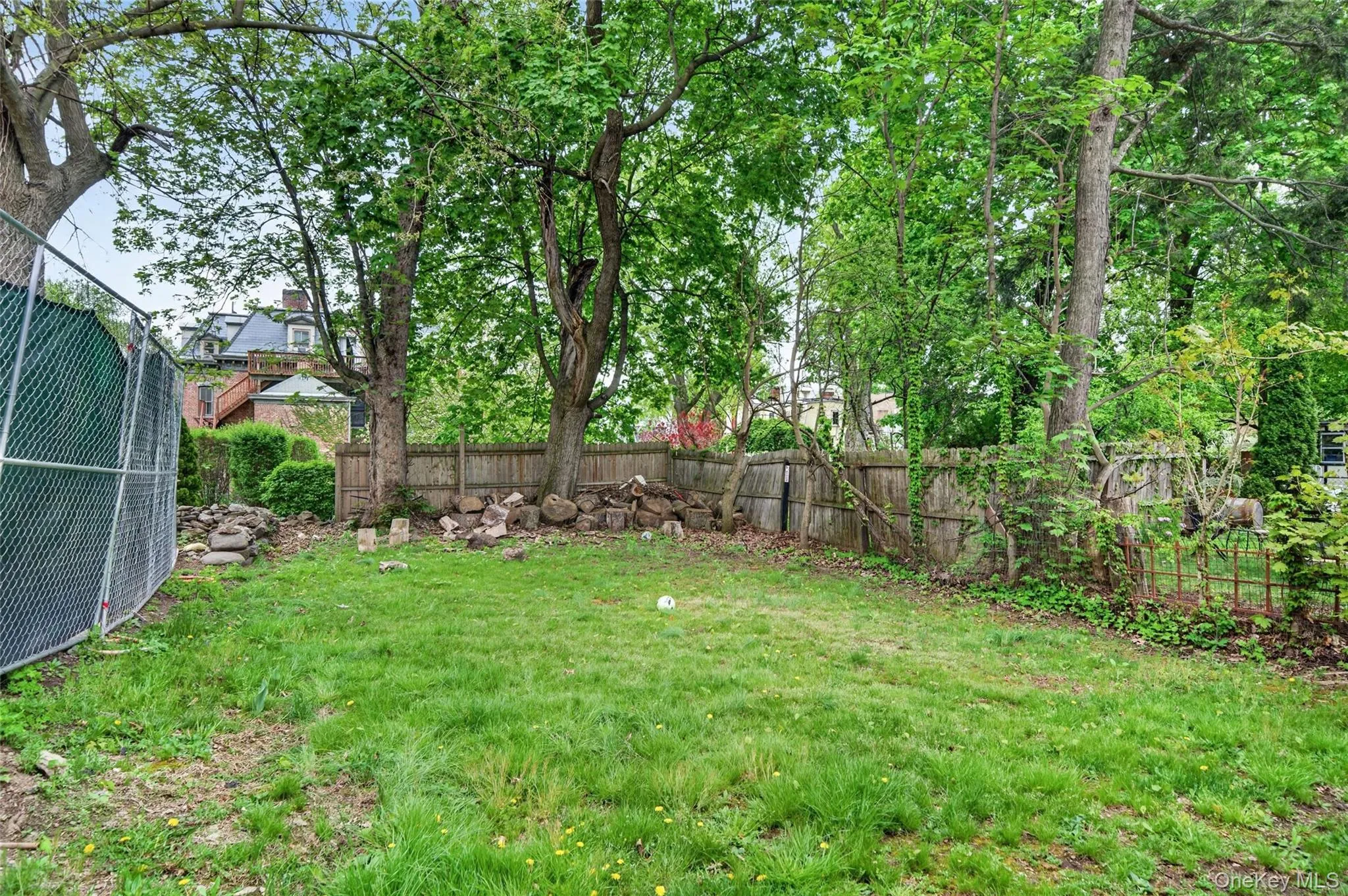 Spacious rear yard featuring natural grass, mature trees, and perimeter fencing Spacious rear yard featuring natural grass, mature trees, and perimeter fencing