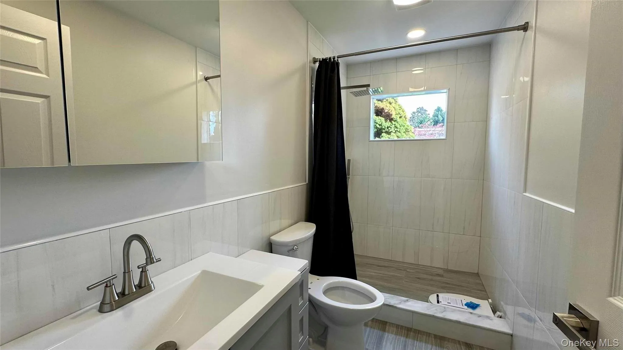 Full bath with a shower stall, toilet, vanity, and a wainscoted wall Full bath with a shower stall, toilet, vanity, and a wainscoted wall