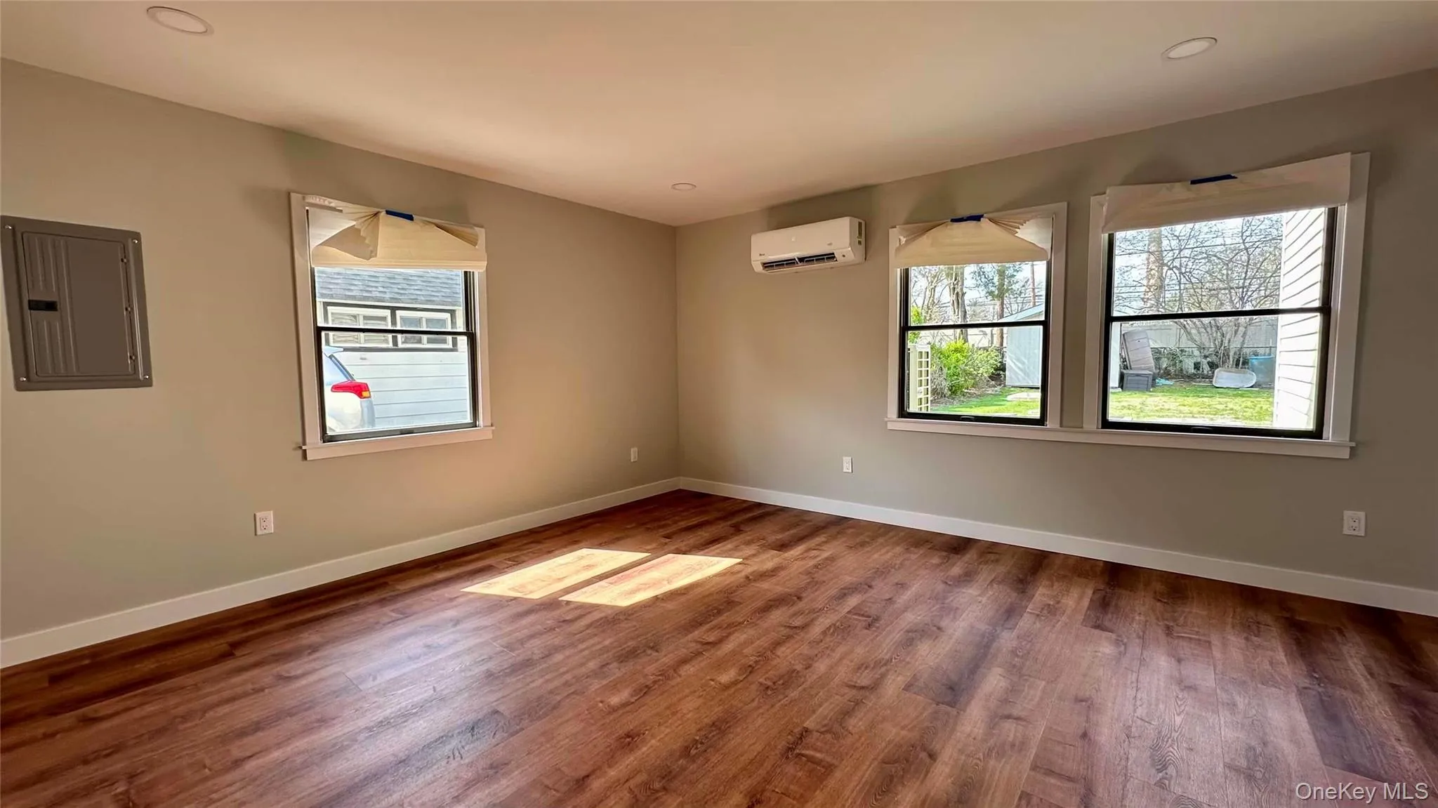 Spare room featuring electric panel, baseboards, wood finished floors, and a wall unit AC Spare room featuring electric panel, baseboards, wood finished floors, and a wall unit AC