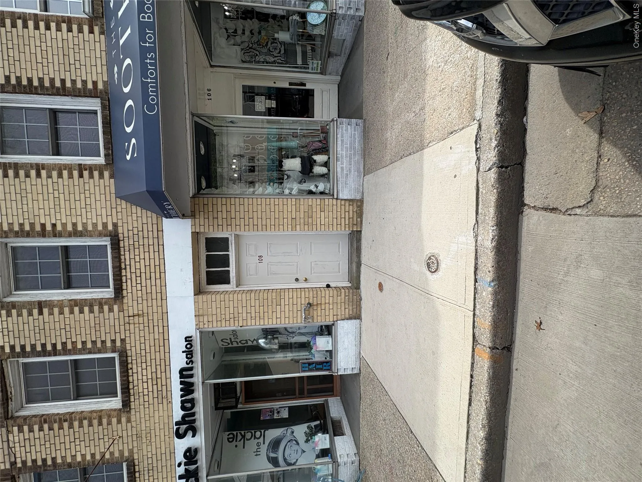 Brick facade building featuring a central entrance with transom window, paired upper-level windows, and retail storefronts Brick facade building featuring a central entrance with transom window, paired upper-level windows, and retail storefronts