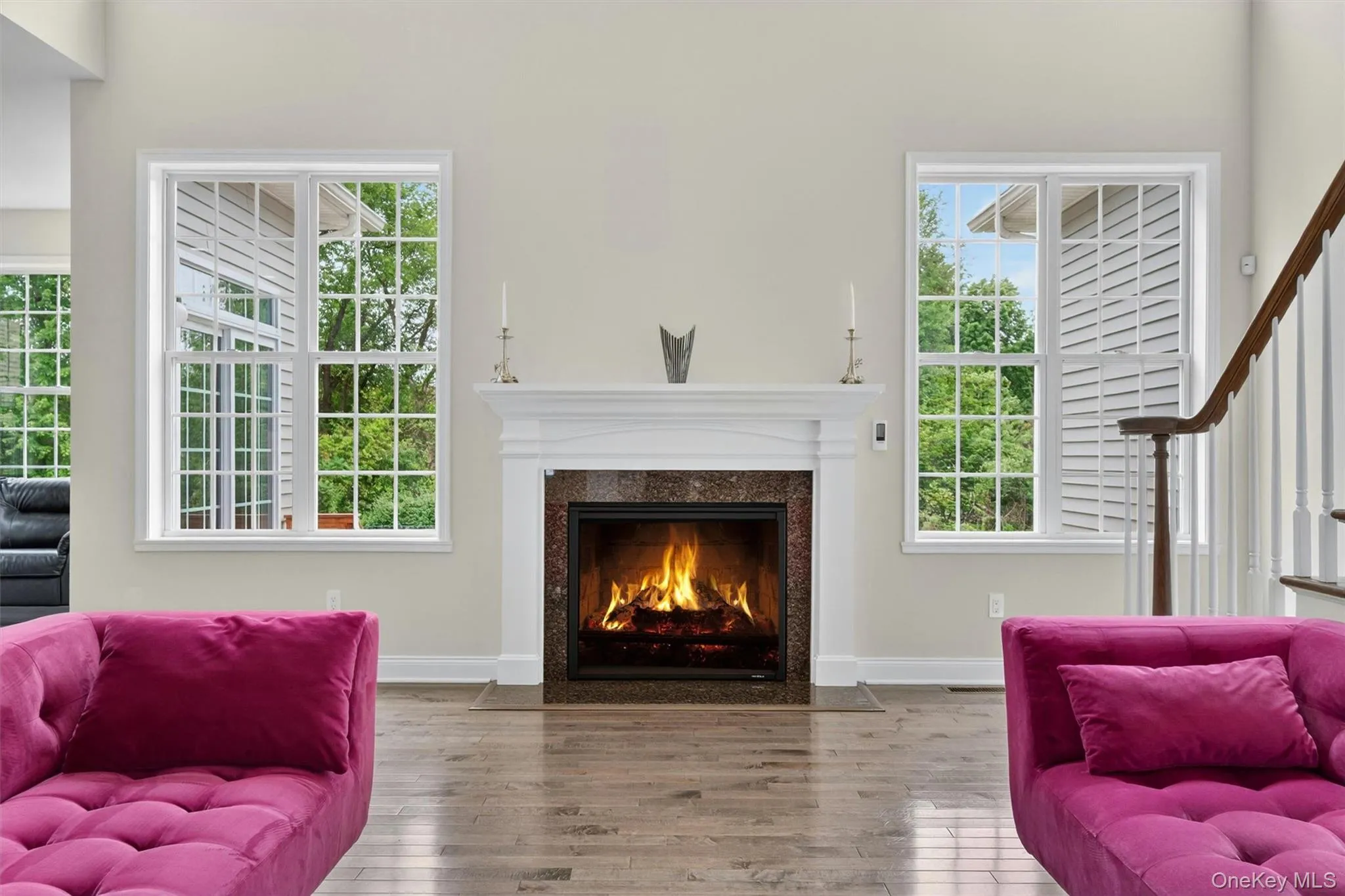 Living Room Gas fireplace with a white mantel and dark stone surround flanked by windows Living Room Gas fireplace with a white mantel and dark stone surround flanked by windows