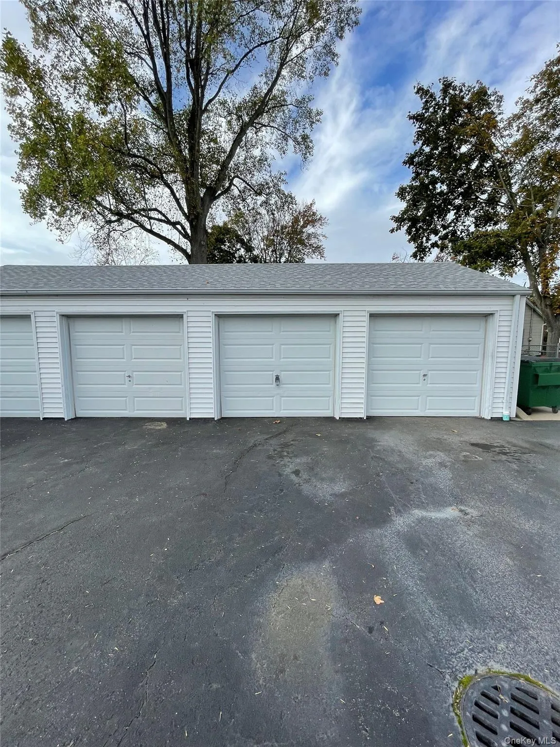 Four-bay detached garage structure featuring light gray panel doors and horizontal white siding Four-bay detached garage structure featuring light gray panel doors and horizontal white siding