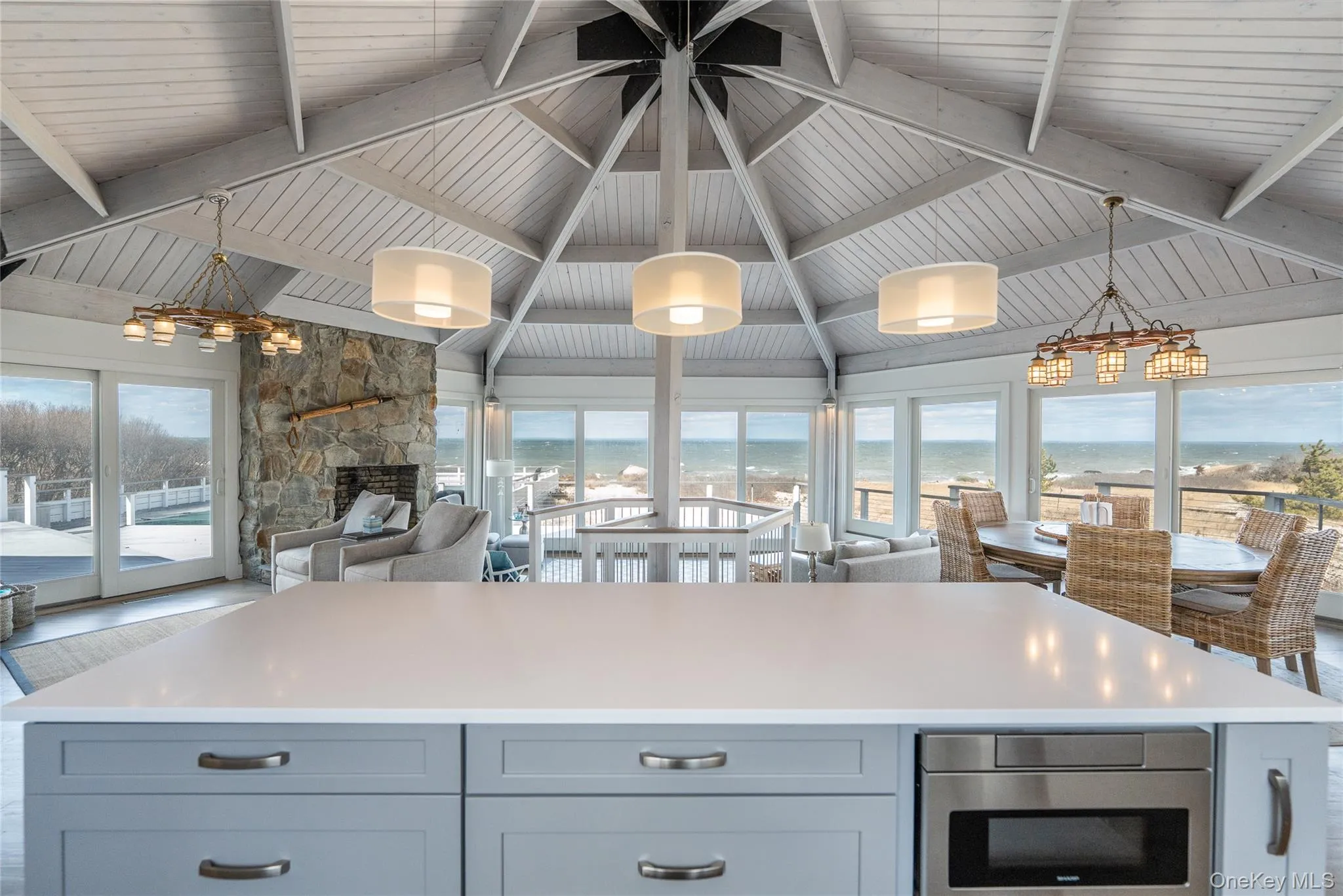 Kitchen featuring lofted ceiling with beams, hanging light fixtures, plenty of natural light, and open floor plan Kitchen featuring lofted ceiling with beams, hanging light fixtures, plenty of natural light, and open floor plan