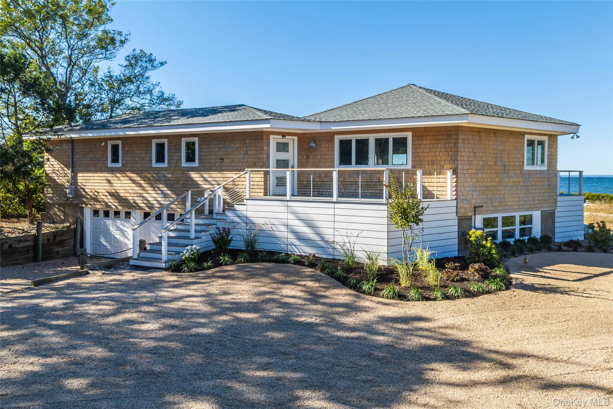 Rear view of house with driveway, an attached garage, stairs, and roof with shingles Rear view of house with driveway, an attached garage, stairs, and roof with shingles