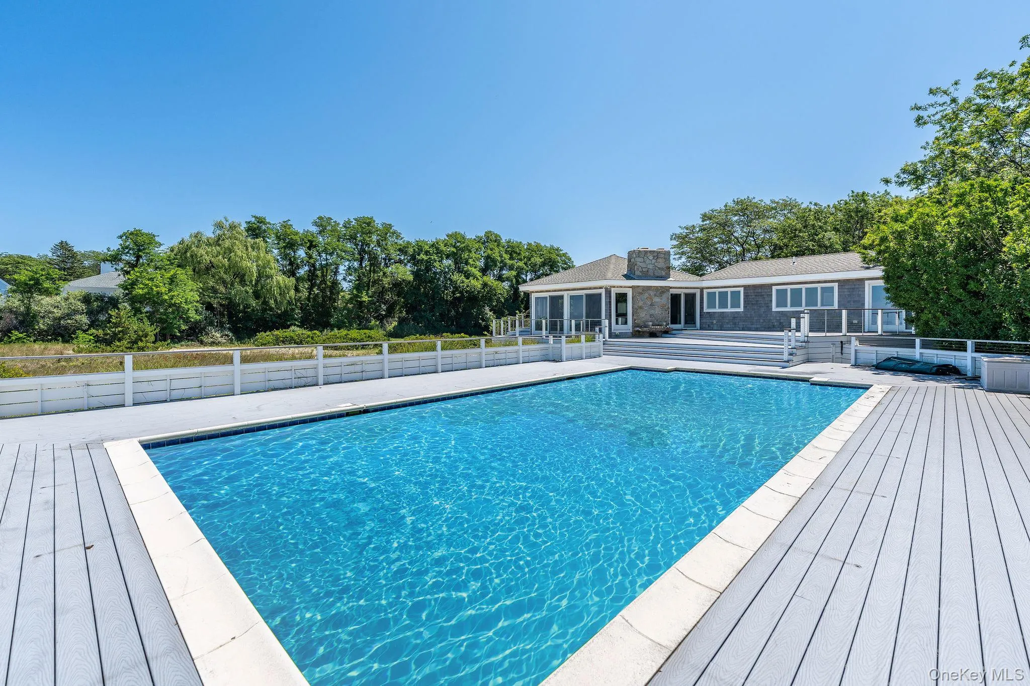 View of swimming pool with a patio area, a deck, and view of scattered trees View of swimming pool with a patio area, a deck, and view of scattered trees