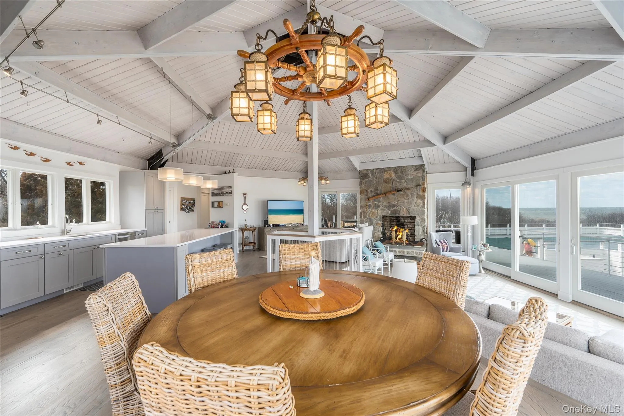 Dining space with light wood-style flooring, rail lighting, a fireplace, beam ceiling, and a notable chandelier Dining space with light wood-style flooring, rail lighting, a fireplace, beam ceiling, and a notable chandelier