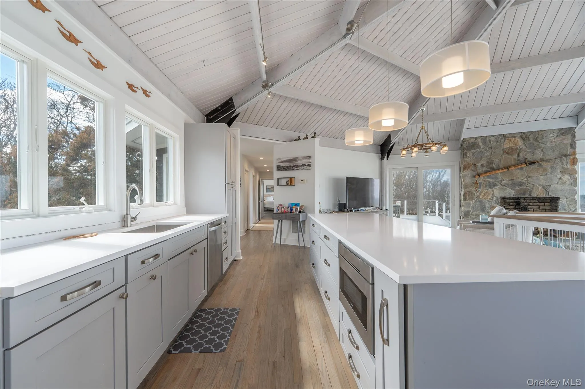 Kitchen featuring a sink, vaulted ceiling with beams, gray cabinetry, light wood-style flooring, and stainless steel appliances Kitchen featuring a sink, vaulted ceiling with beams, gray cabinetry, light wood-style flooring, and stainless steel appliances