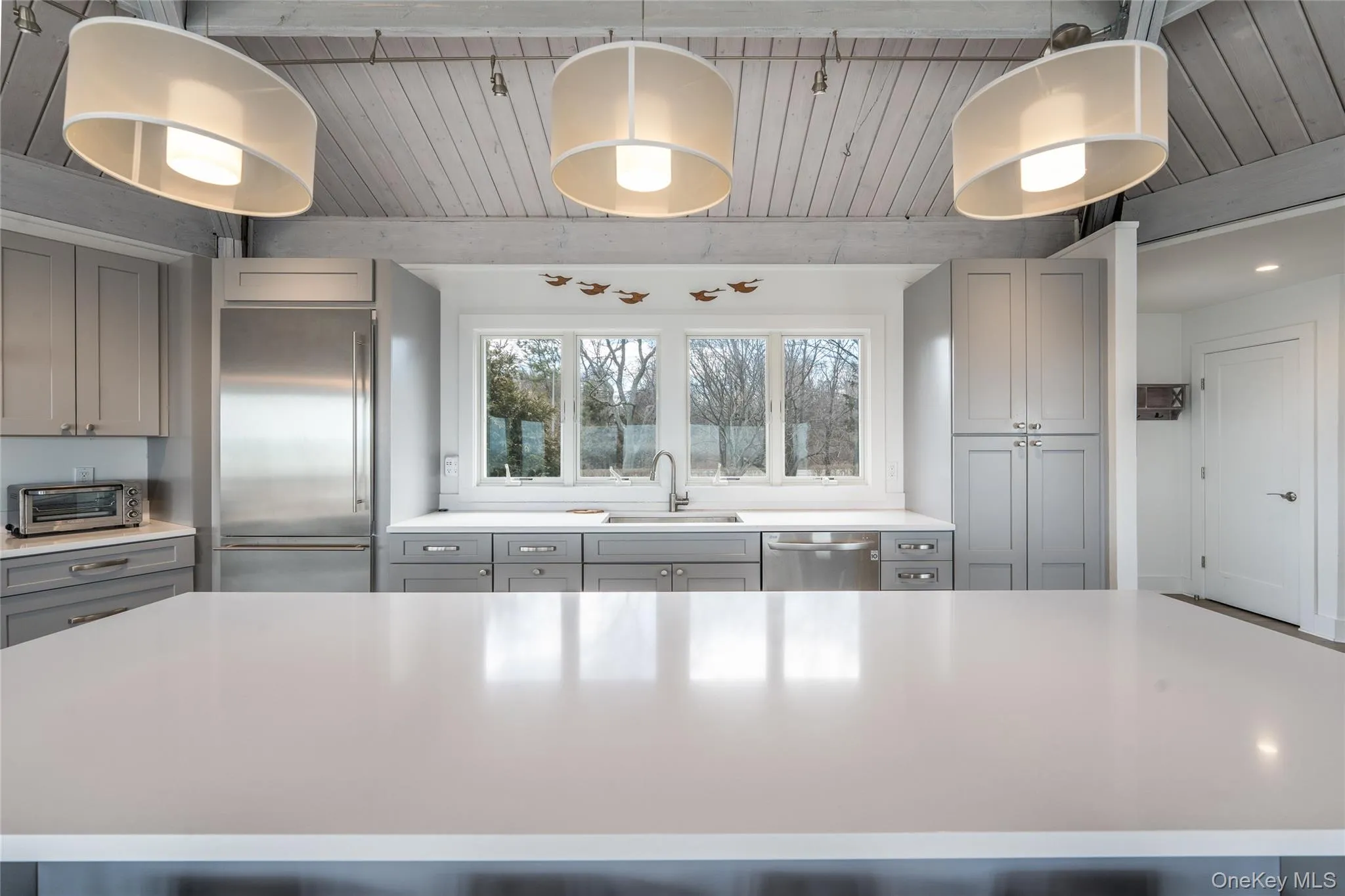 Kitchen featuring gray cabinetry, light countertops, a sink, and appliances with stainless steel finishes Kitchen featuring gray cabinetry, light countertops, a sink, and appliances with stainless steel finishes