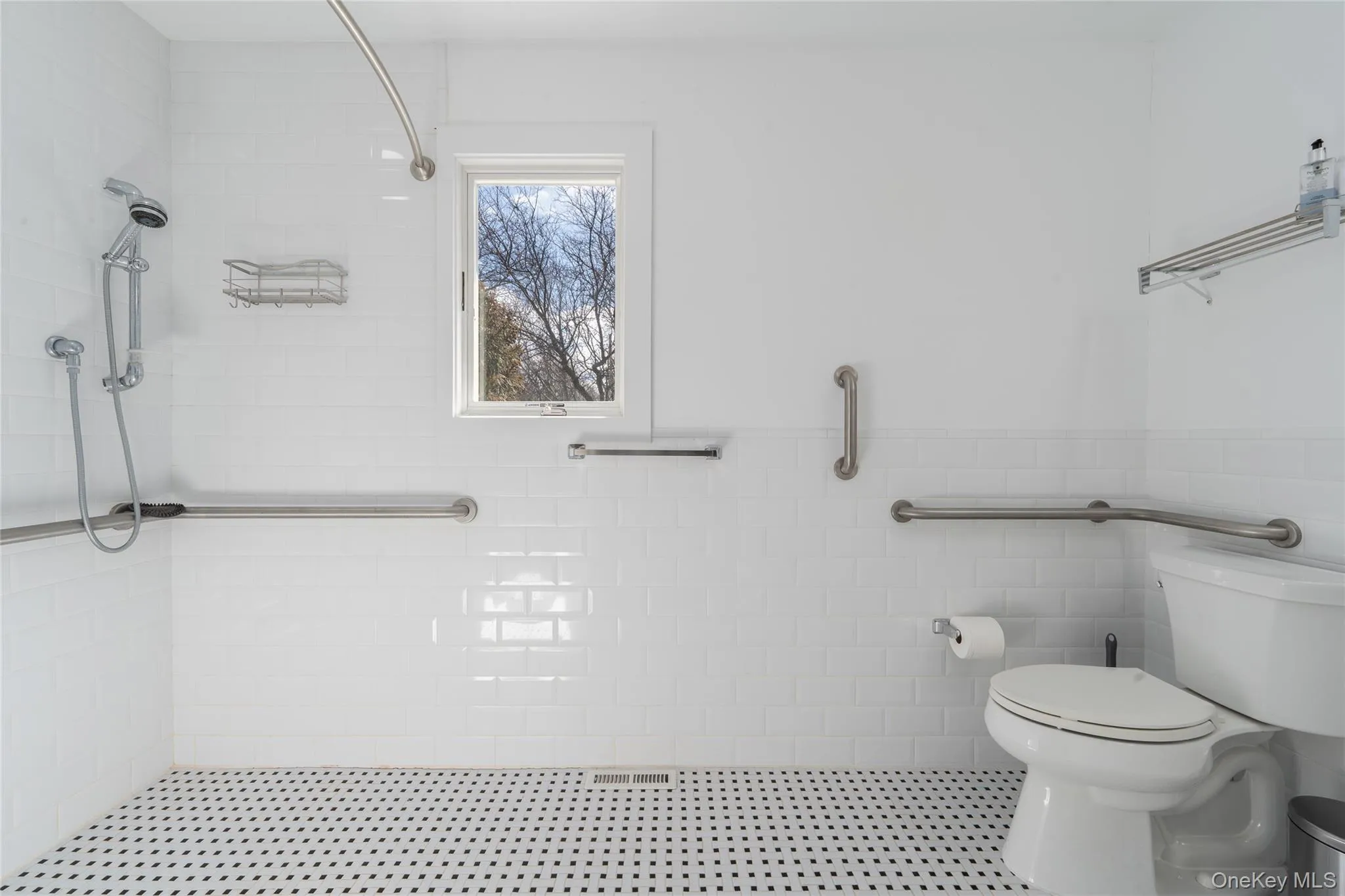 Bathroom with tile walls, a wainscoted wall, toilet, and tiled shower Bathroom with tile walls, a wainscoted wall, toilet, and tiled shower