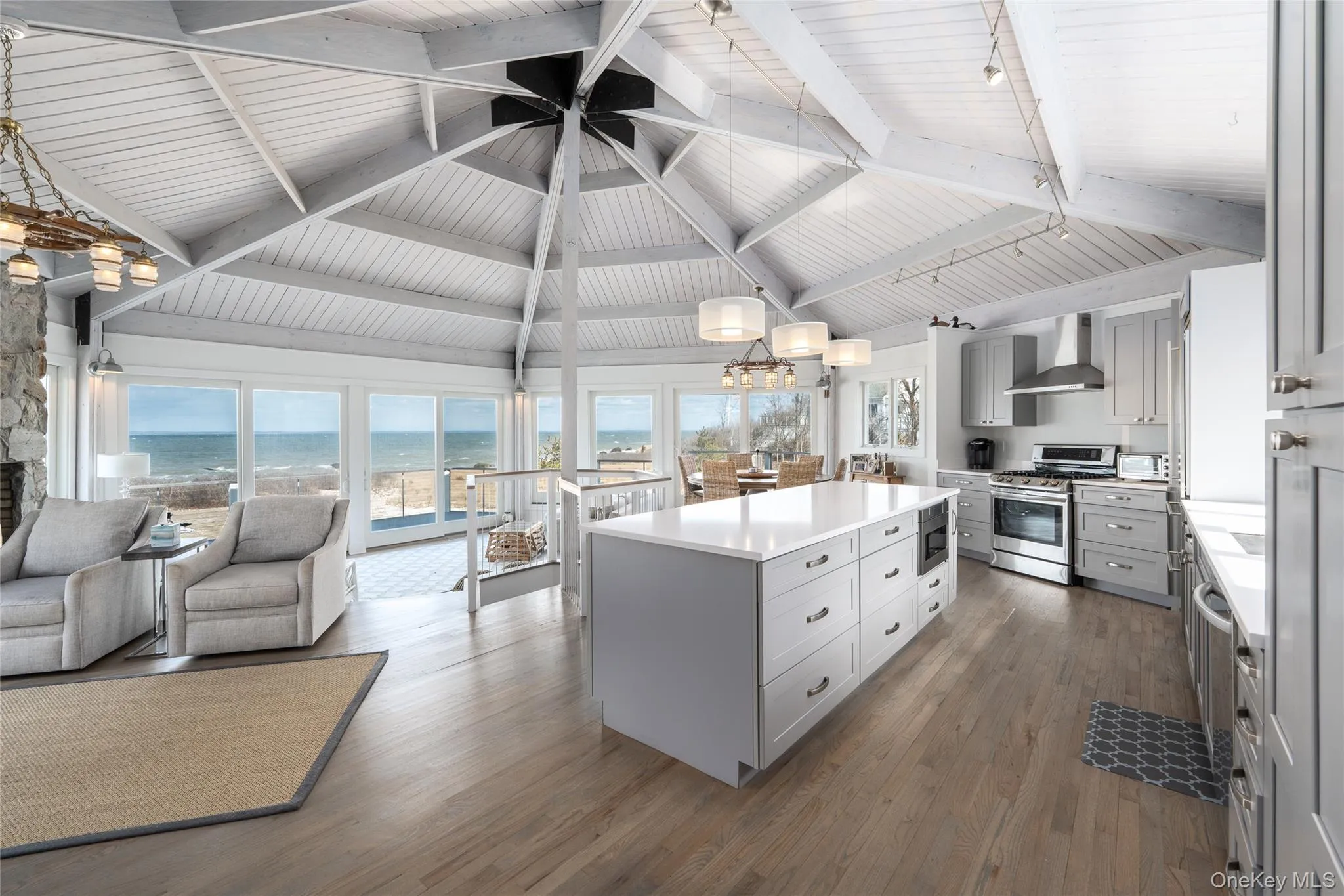 Kitchen featuring stainless steel appliances, open floor plan, dark wood-style floors, wall chimney range hood, and gray cabinets Kitchen featuring stainless steel appliances, open floor plan, dark wood-style floors, wall chimney range hood, and gray cabinets