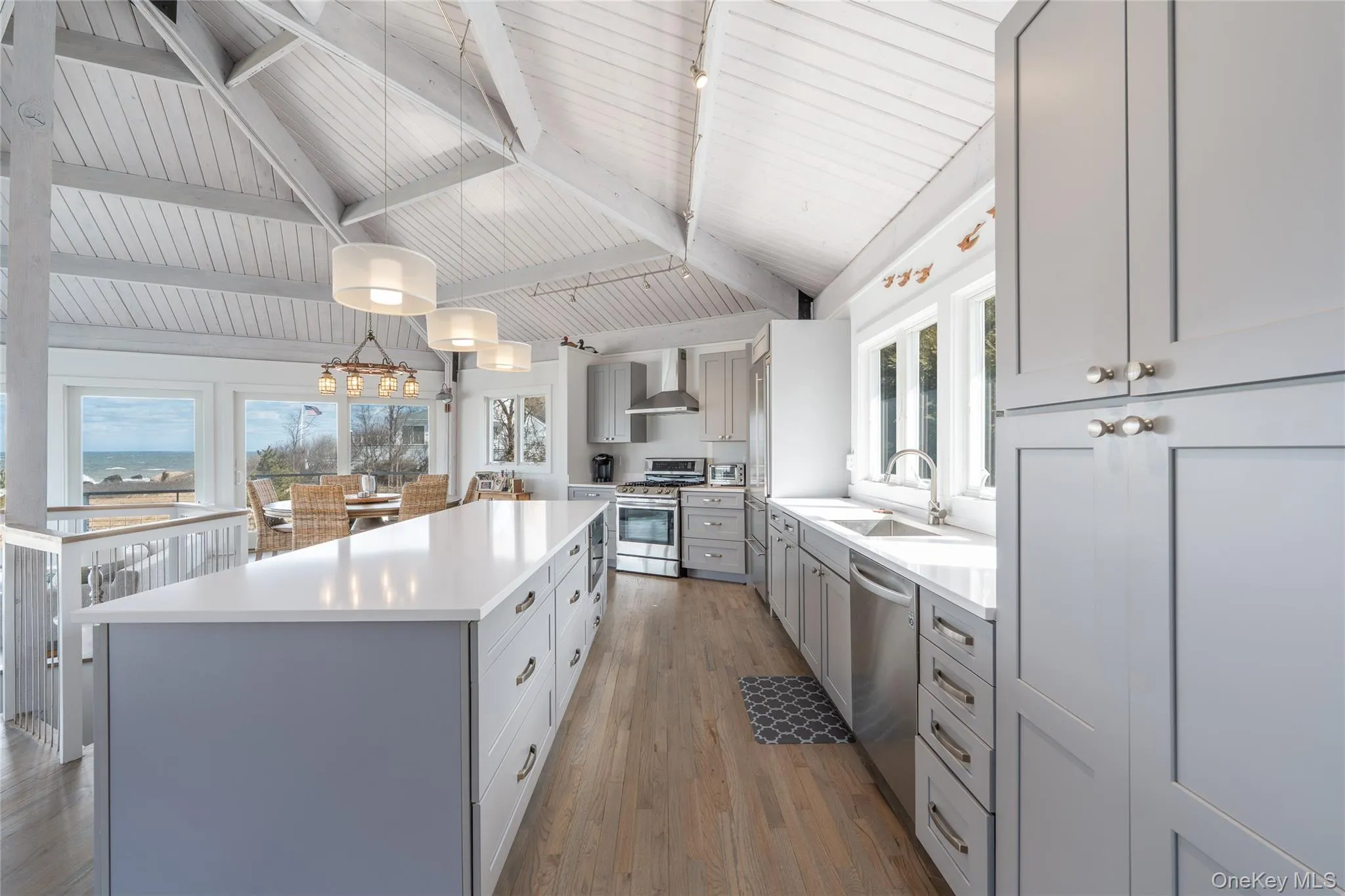 Kitchen featuring a sink, wood finished floors, a center island, stainless steel appliances, and wall chimney range hood Kitchen featuring a sink, wood finished floors, a center island, stainless steel appliances, and wall chimney range hood