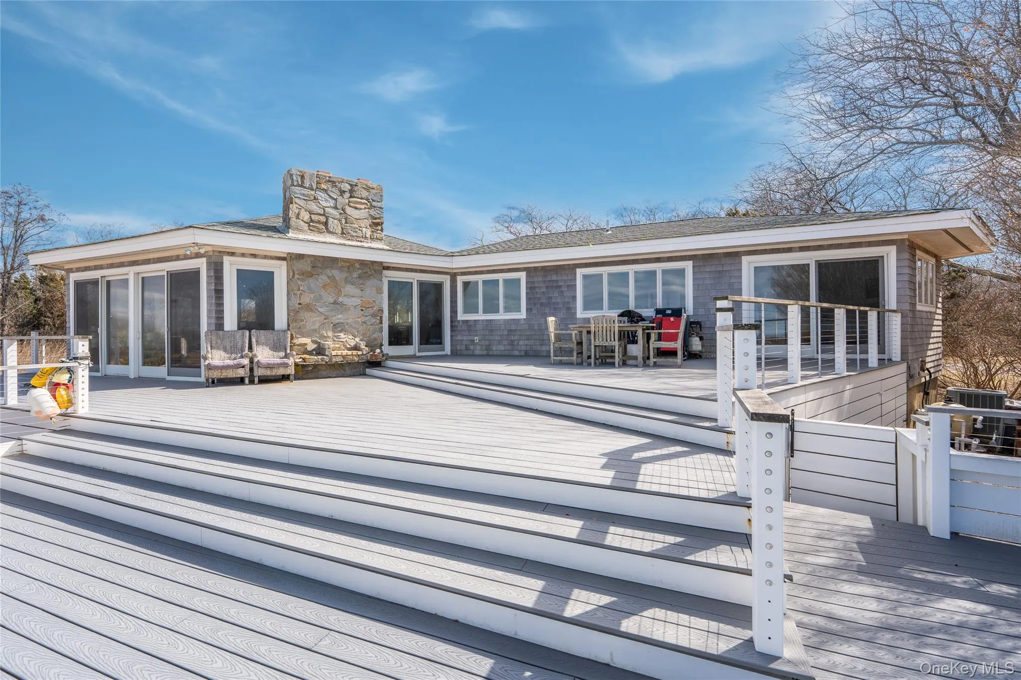 Back of property with a chimney, a sunroom, and a wooden deck Back of property with a chimney, a sunroom, and a wooden deck