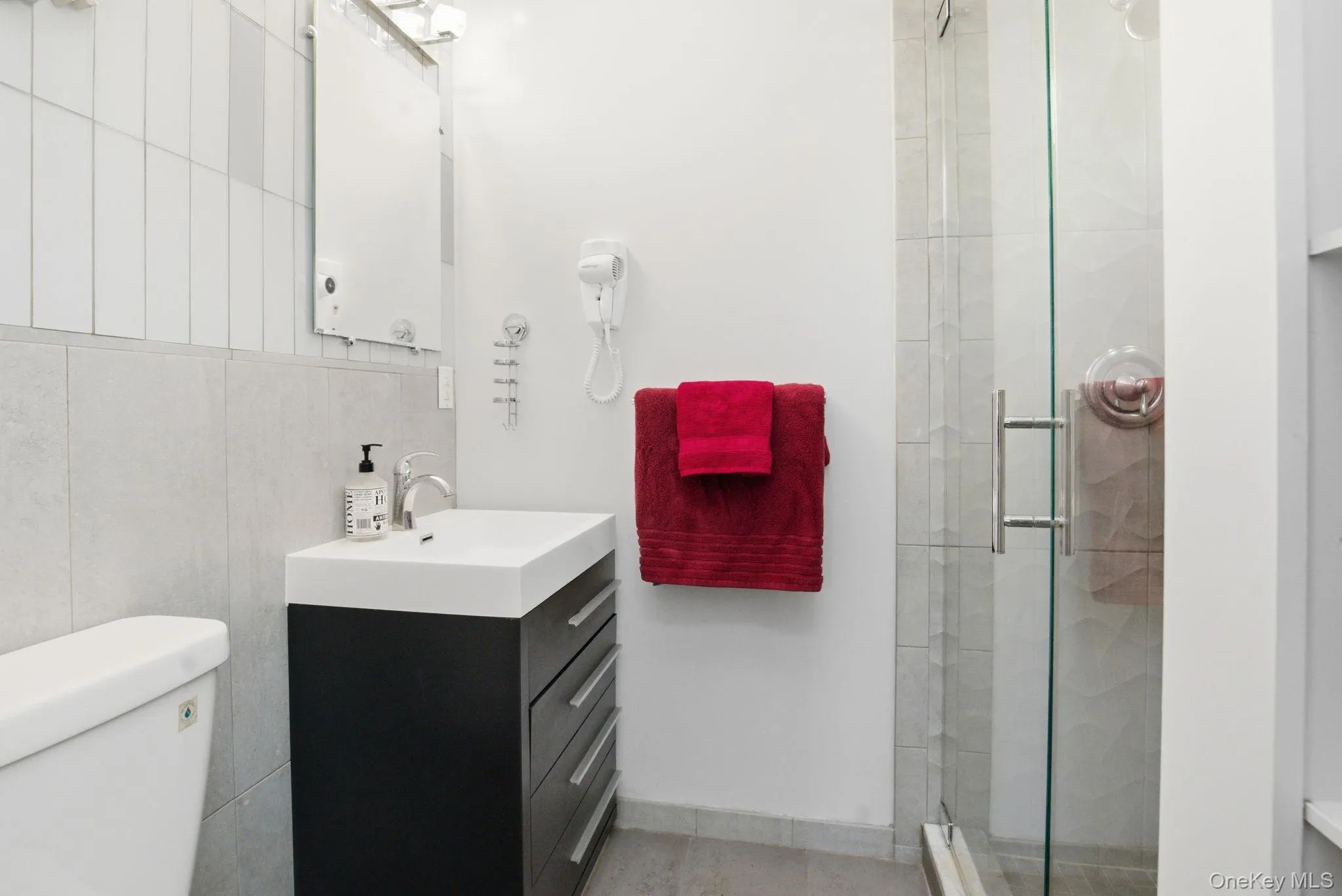 The private en suite bath is freshly updated with a glass shower, sleek vanity, and crisp tilework. The private en suite bath is freshly updated with a glass shower, sleek vanity, and crisp tilework.