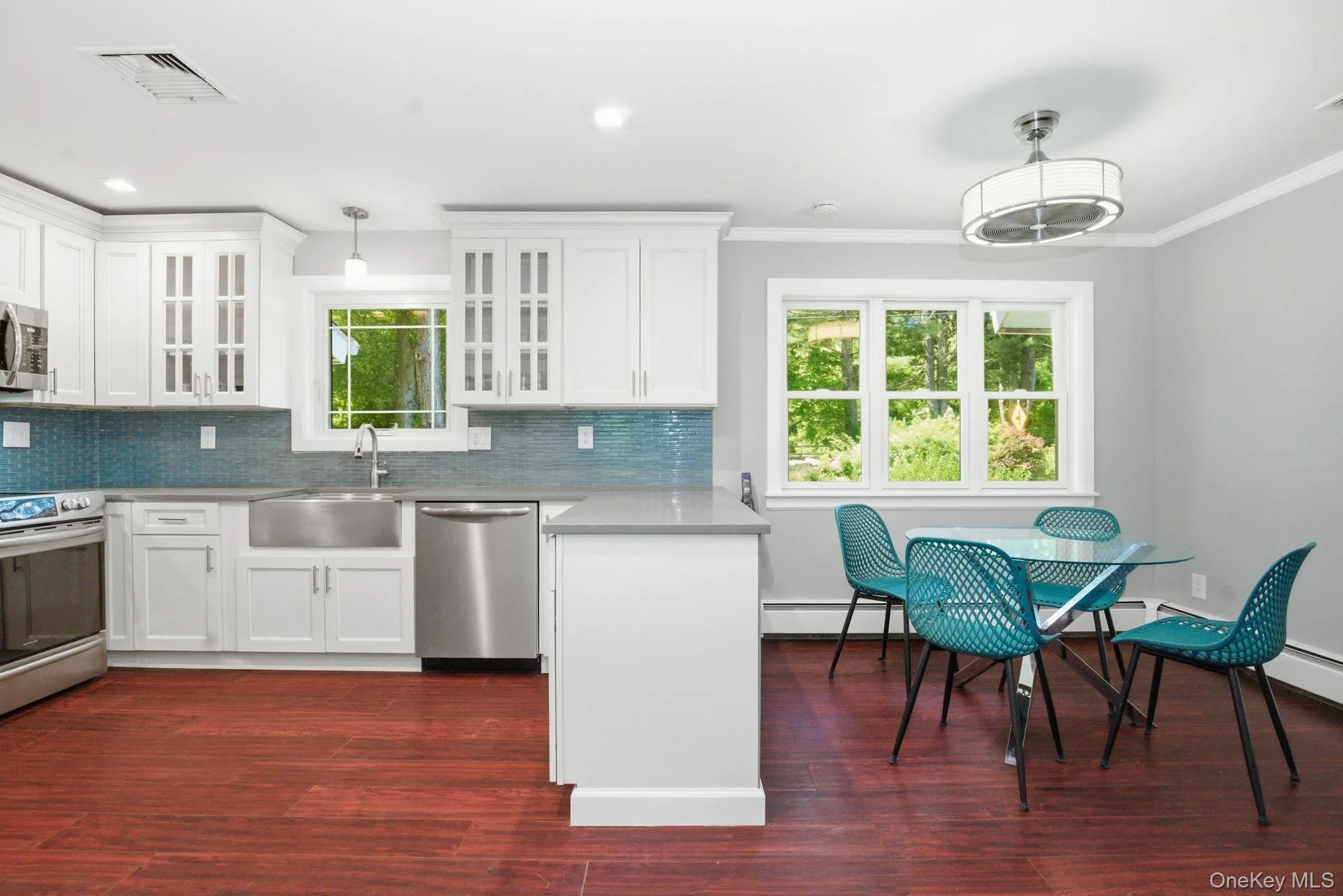 The fully renovated kitchen pairs crisp white cabinetry with quartz counters and a striking glass tile backsplash. The fully renovated kitchen pairs crisp white cabinetry with quartz counters and a striking glass tile backsplash.