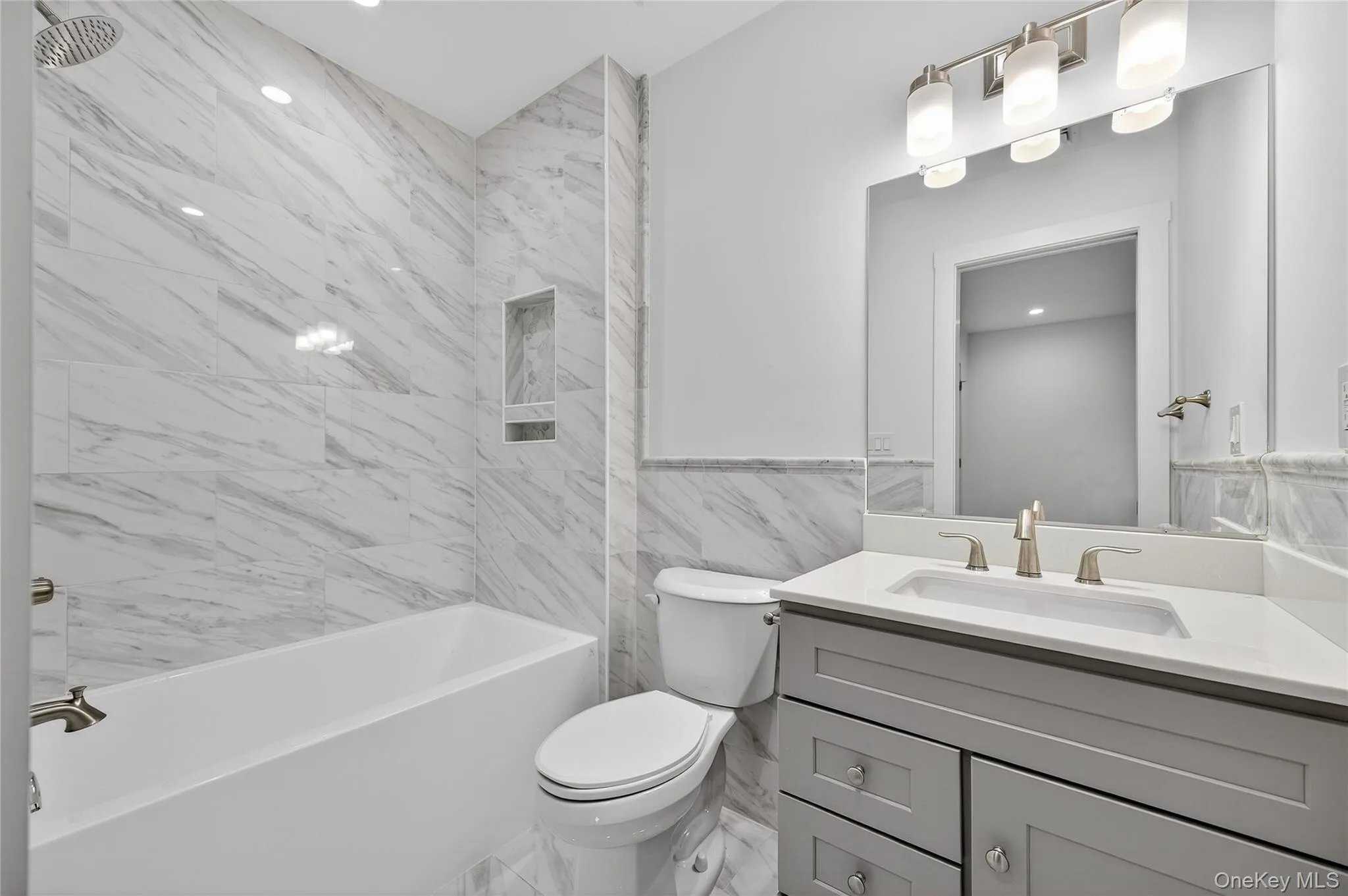 Bathroom with tile walls, shower / tub combination, vanity, recessed lighting, and wainscoting Bathroom with tile walls, shower / tub combination, vanity, recessed lighting, and wainscoting