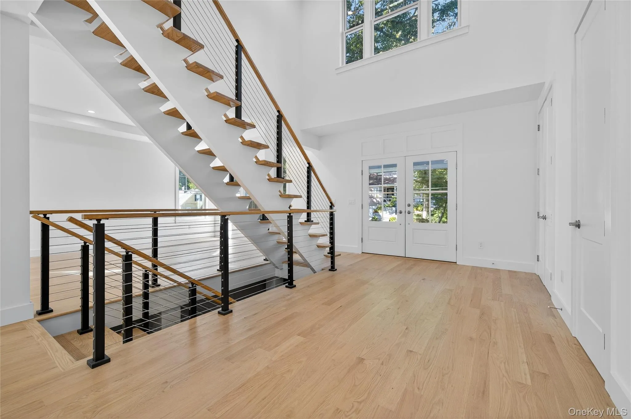 Foyer featuring light wood-type flooring, a towering ceiling, and french doors Foyer featuring light wood-type flooring, a towering ceiling, and french doors