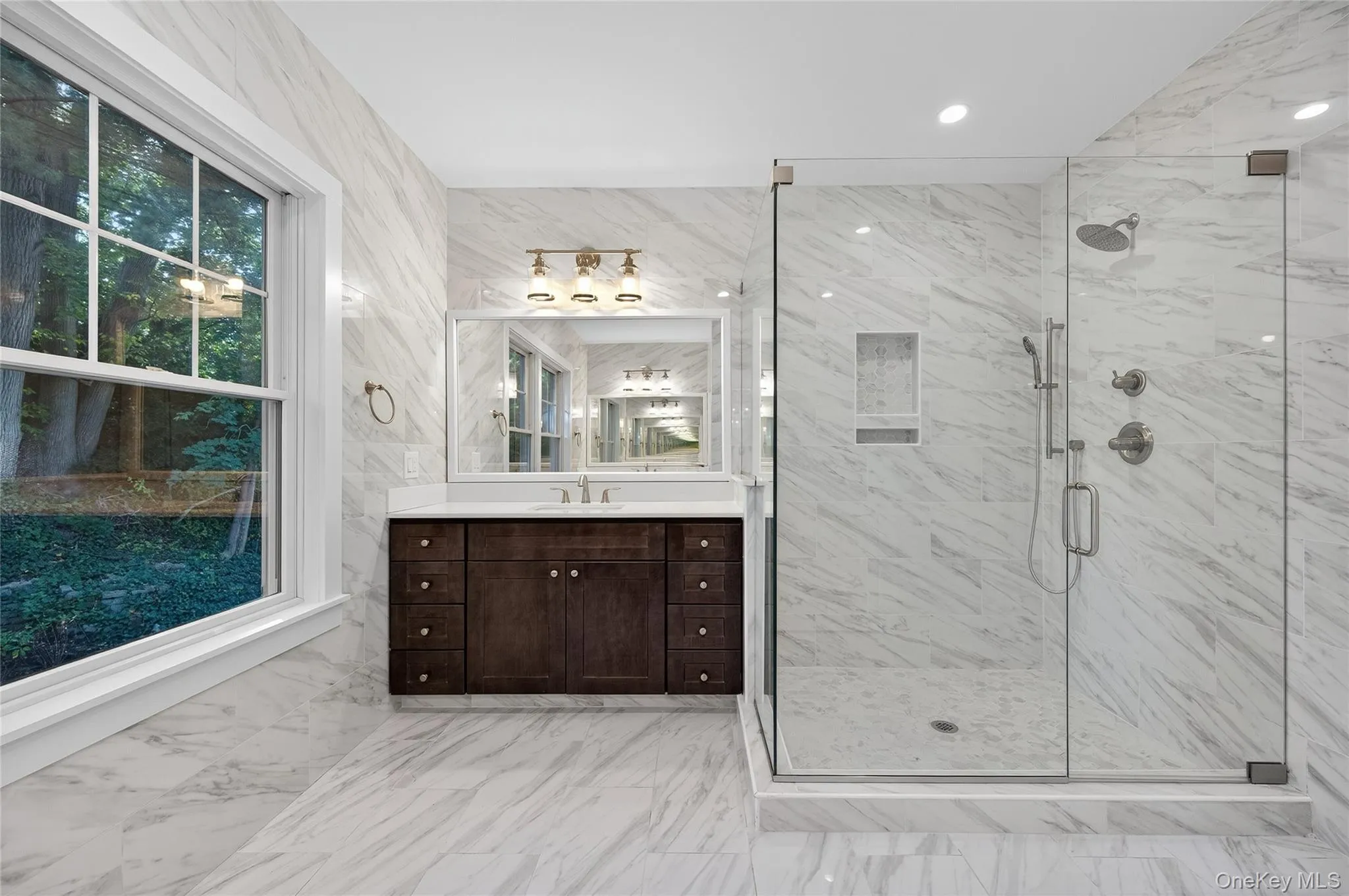 Bathroom with tile walls, vanity, a marble finish shower, light marble finish flooring, and recessed lighting Bathroom with tile walls, vanity, a marble finish shower, light marble finish flooring, and recessed lighting