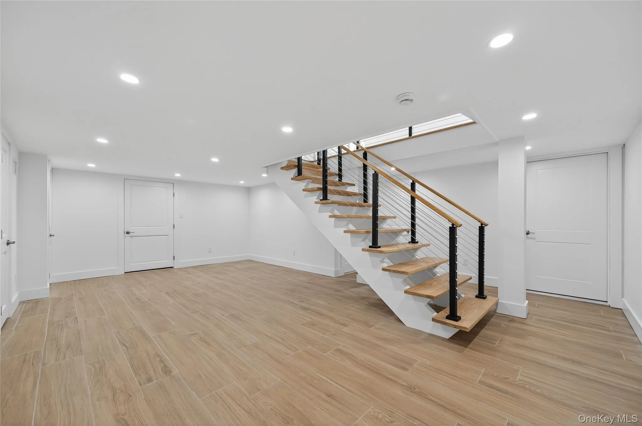 Finished below grade area with light wood-type flooring, recessed lighting, and stairway Finished below grade area with light wood-type flooring, recessed lighting, and stairway