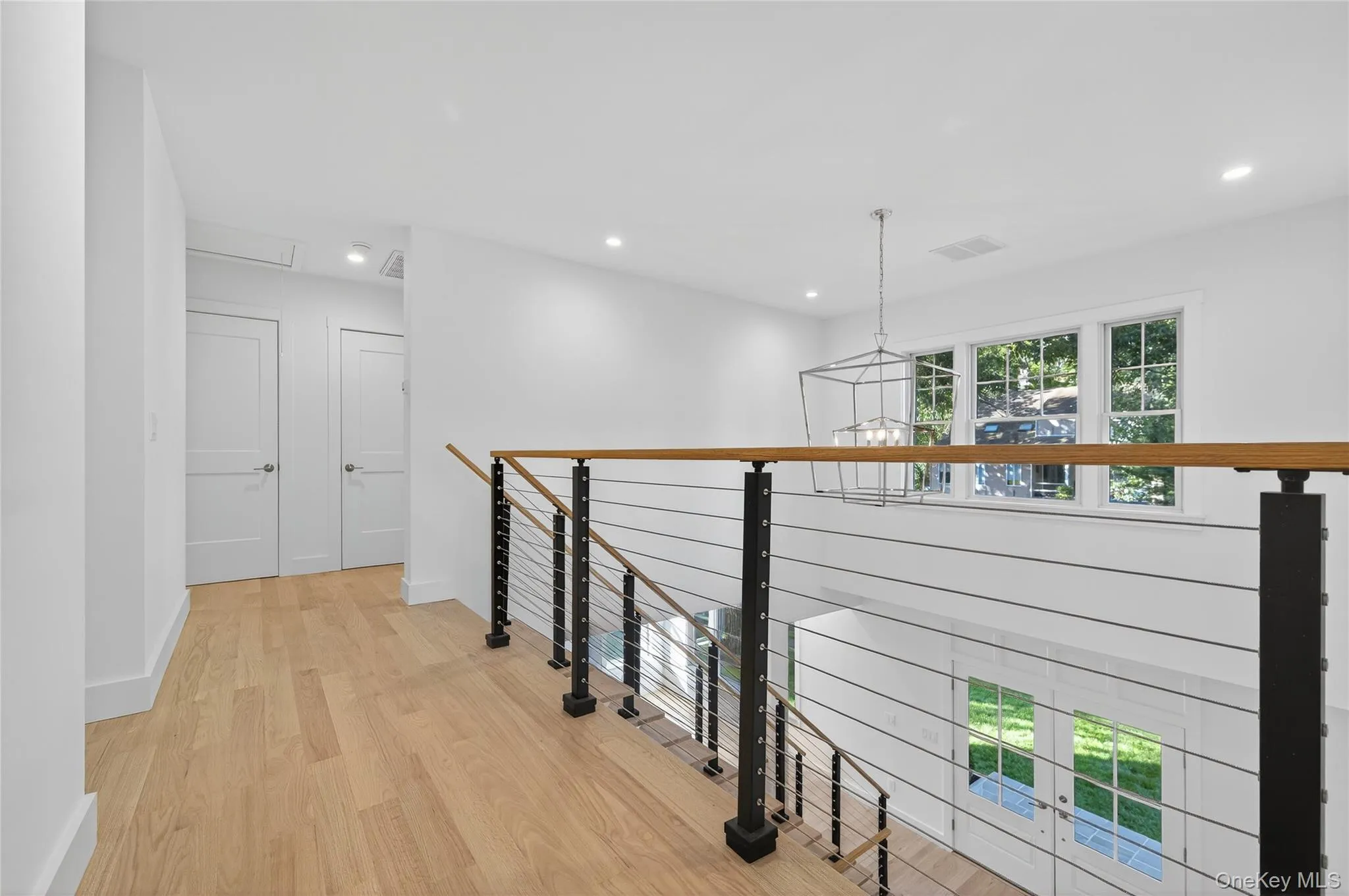 Corridor with light wood-style flooring, recessed lighting, an upstairs landing, and a chandelier Corridor with light wood-style flooring, recessed lighting, an upstairs landing, and a chandelier