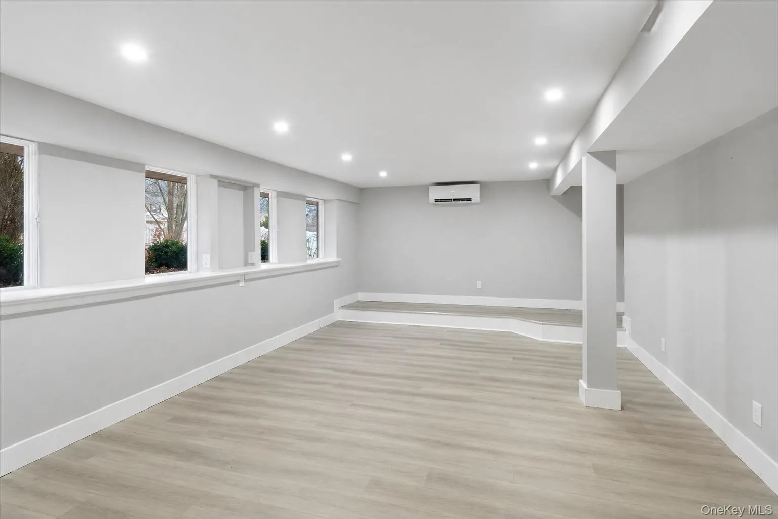 Spacious room featuring light wood-finish flooring, recessed lighting, and multiple windows Spacious room featuring light wood-finish flooring, recessed lighting, and multiple windows