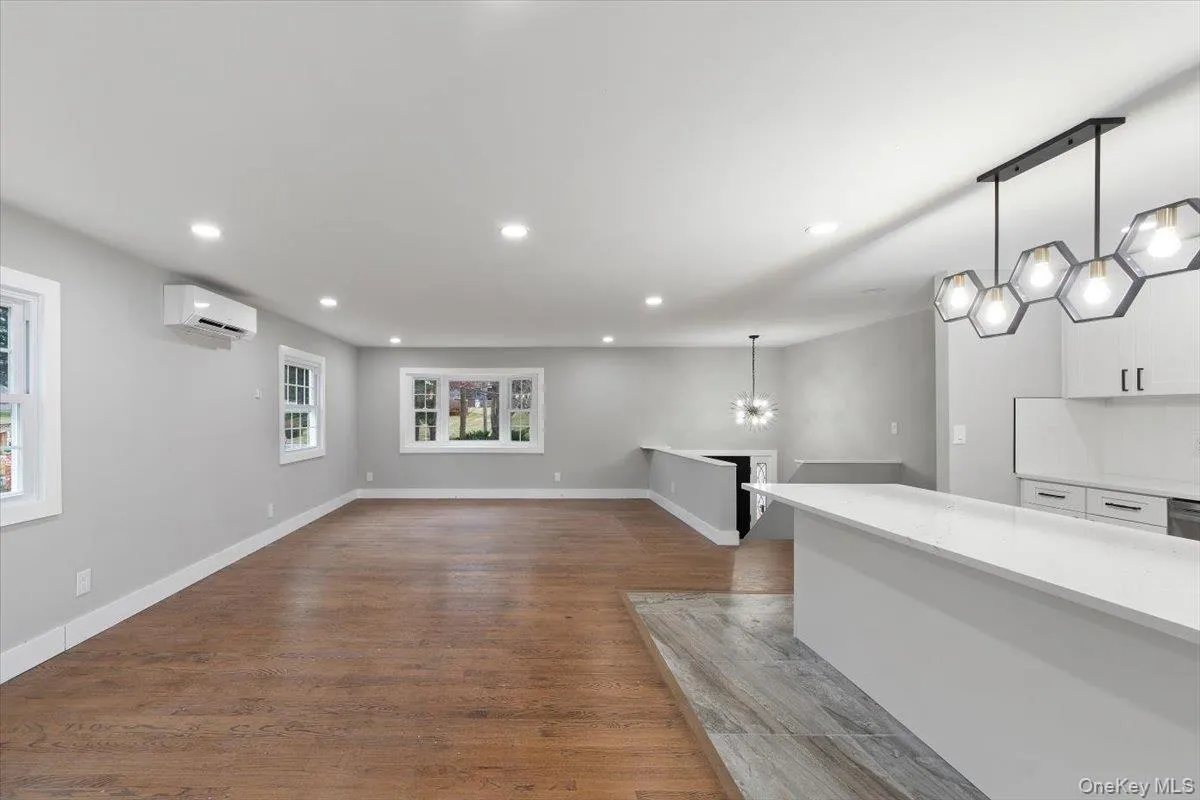 Expansive open-concept living space featuring wood-finish flooring, recessed lighting, and multiple windows Expansive open-concept living space featuring wood-finish flooring, recessed lighting, and multiple windows