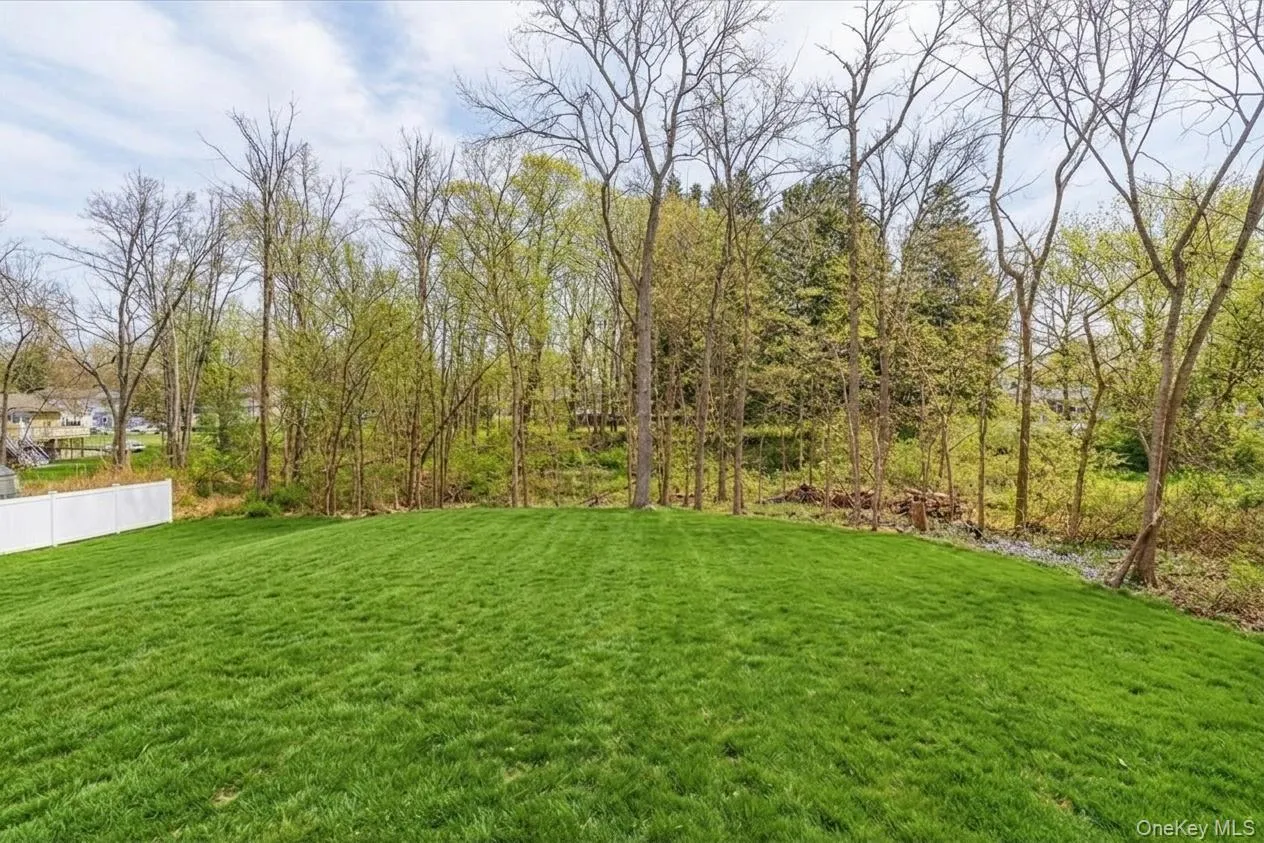 Expansive green lawn with a gentle slope and mature trees bordering the property Expansive green lawn with a gentle slope and mature trees bordering the property