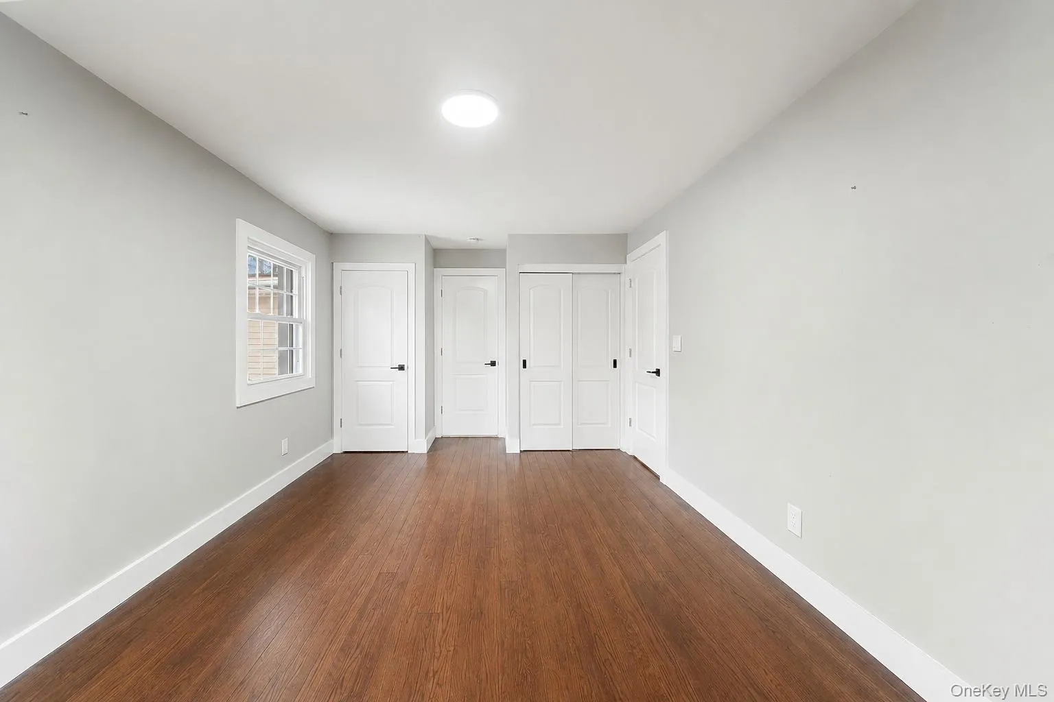 Bright room with wood-finish flooring, white trim, and light gray walls Bright room with wood-finish flooring, white trim, and light gray walls