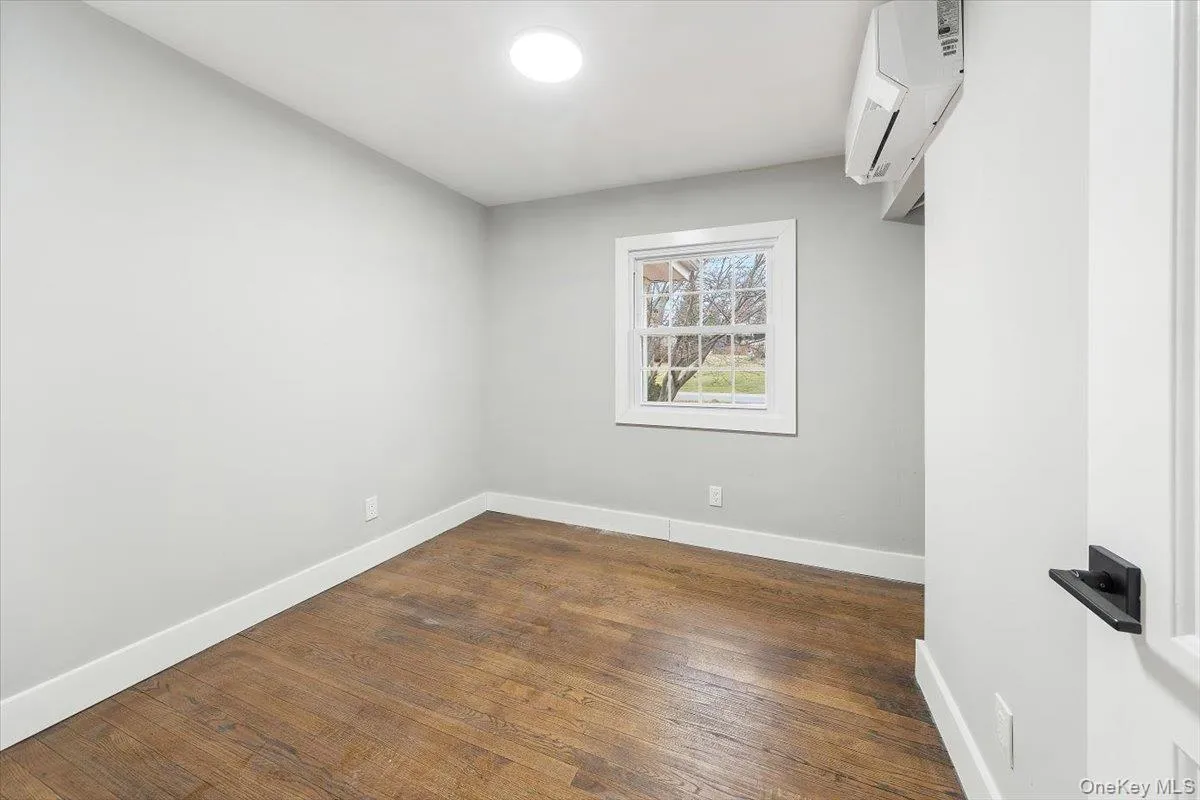 3rd bedroom (main floor) featuring rich wood-finish flooring, light gray walls, and white trim 3rd bedroom (main floor) featuring rich wood-finish flooring, light gray walls, and white trim