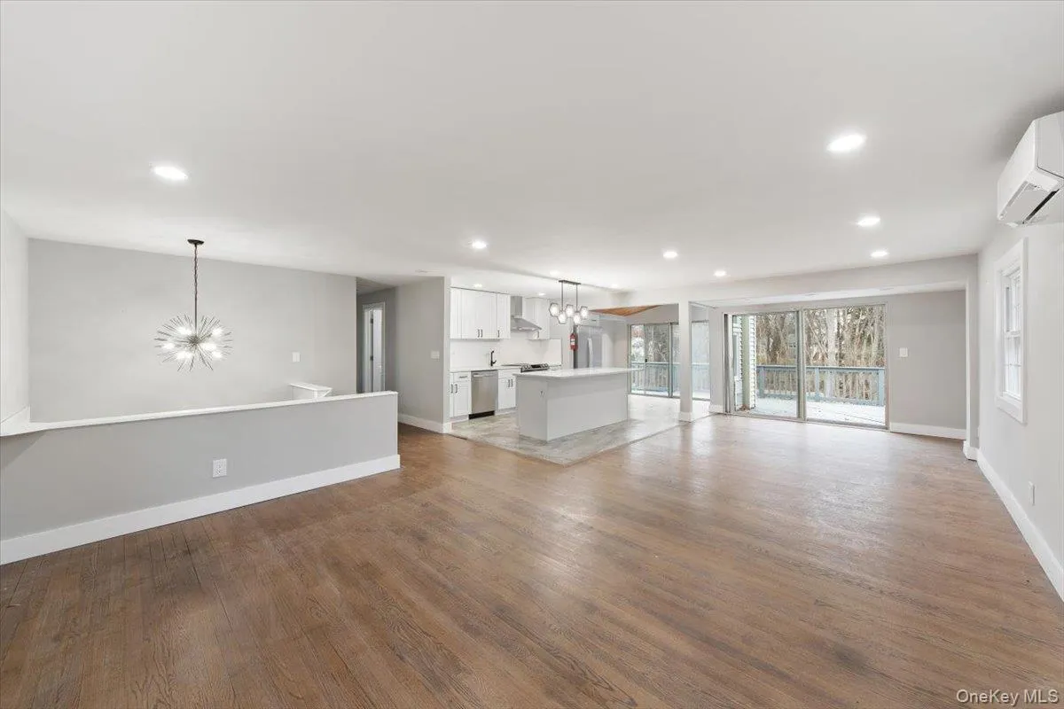 Open-concept living space featuring wood-finish flooring, recessed lighting, and a modern kitchen with a central island Open-concept living space featuring wood-finish flooring, recessed lighting, and a modern kitchen with a central island