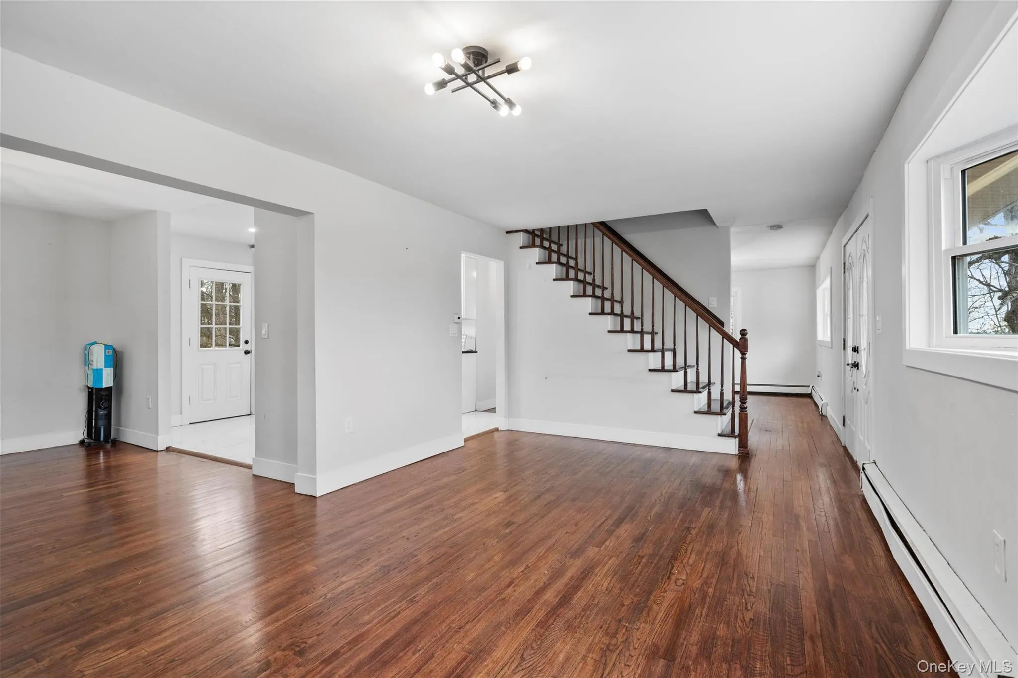 Foyer featuring stairs, wood finished floors, baseboards, and a baseboard radiator Foyer featuring stairs, wood finished floors, baseboards, and a baseboard radiator