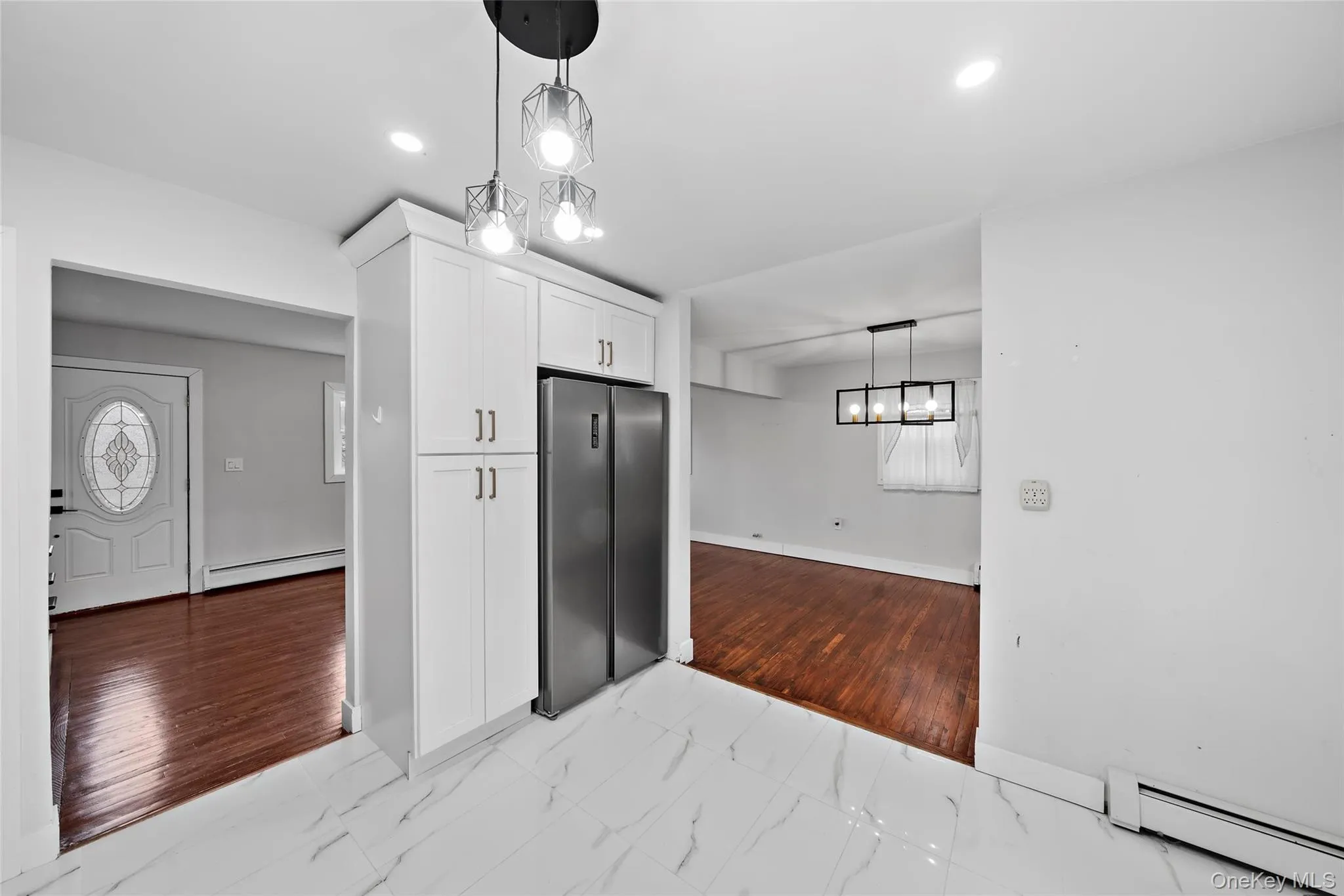 Kitchen featuring white cabinets, baseboards, marble finish floor, and a baseboard radiator Kitchen featuring white cabinets, baseboards, marble finish floor, and a baseboard radiator